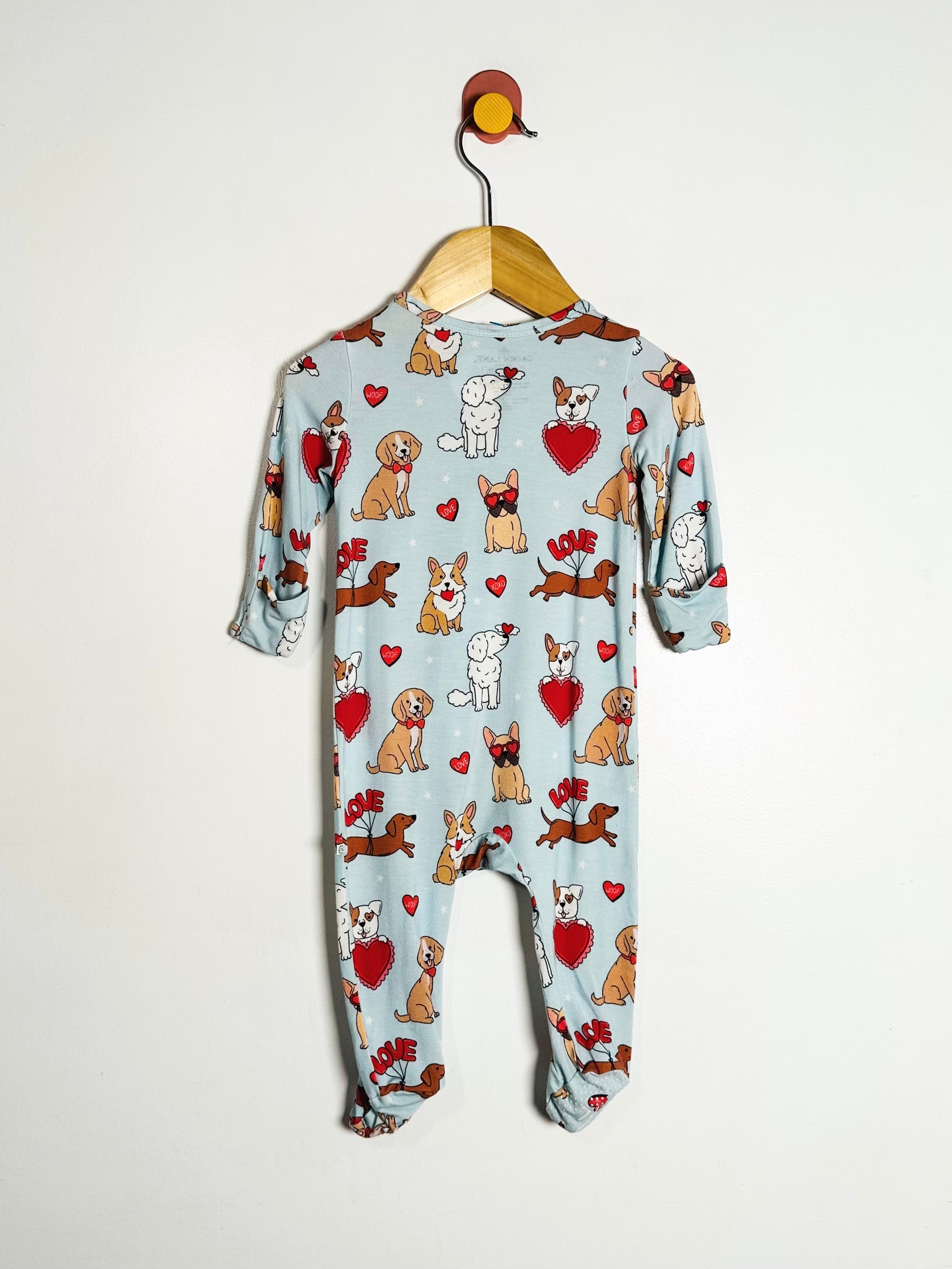 Baby onesie with dog pattern on a hanger against a white background