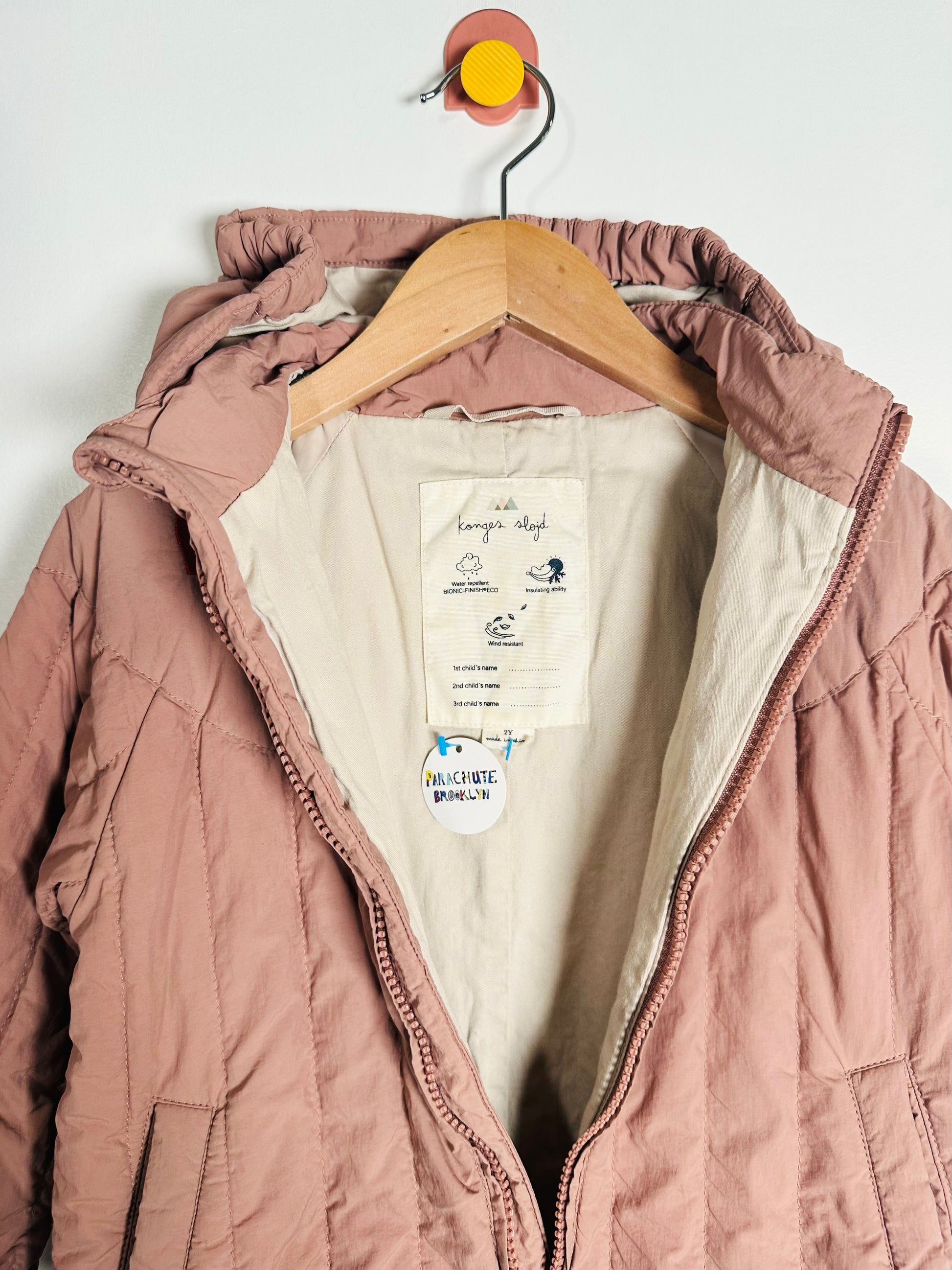 Pink quilted jacket on a hanger with a visible brand label against a white background