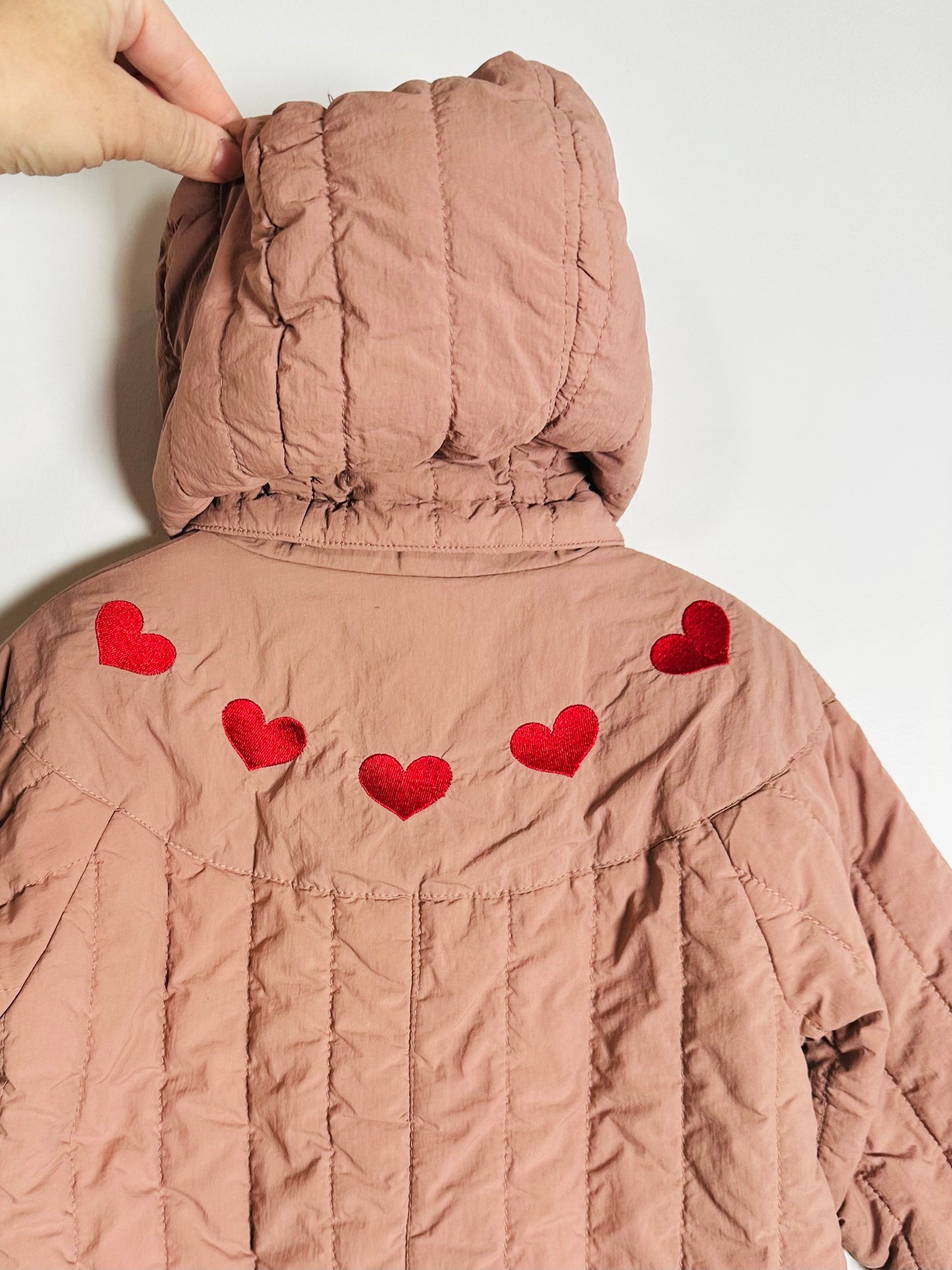 quilted jacket with red heart patterns on a white background