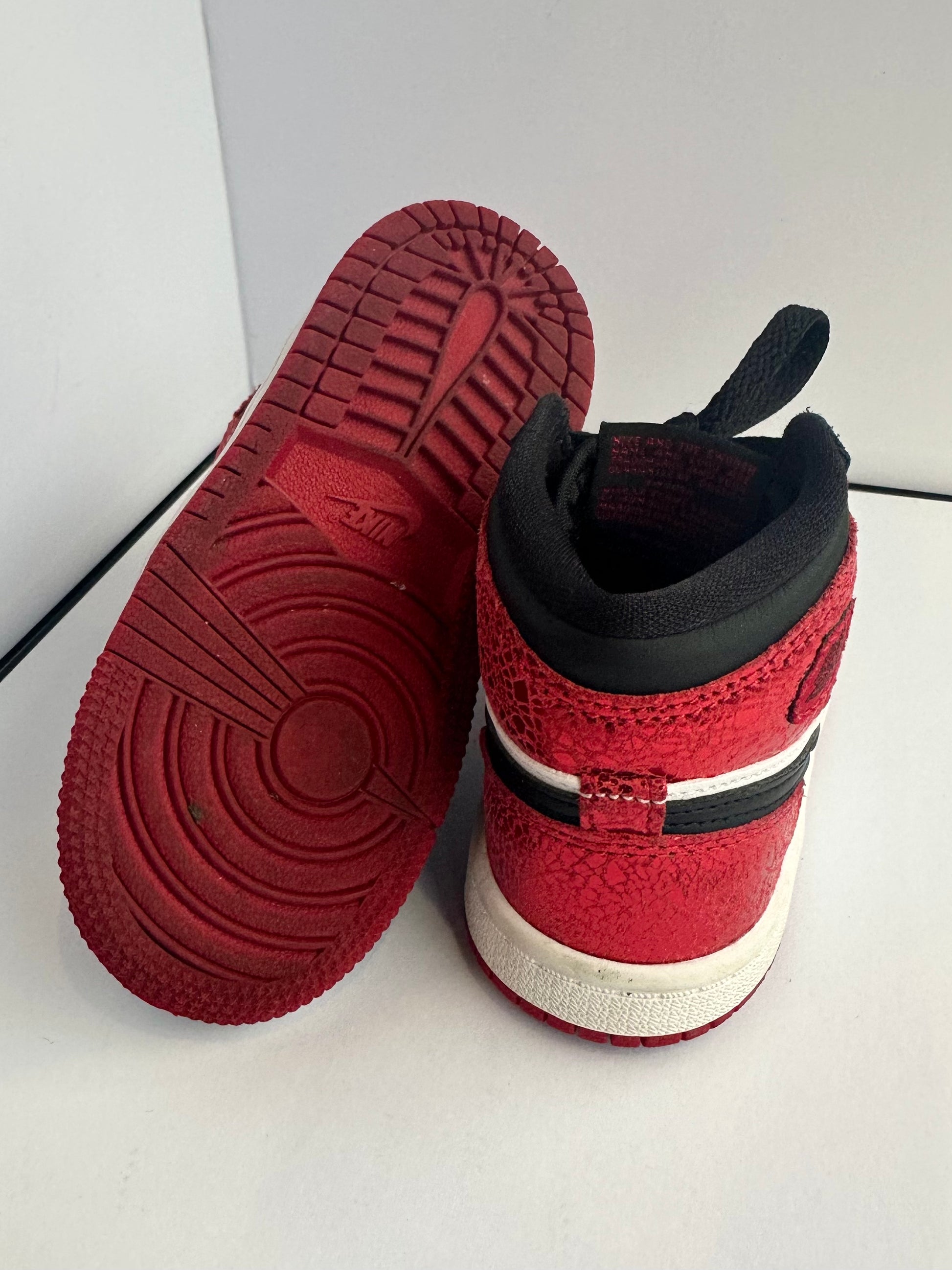 Red and black sneaker with white sole on a light gray background