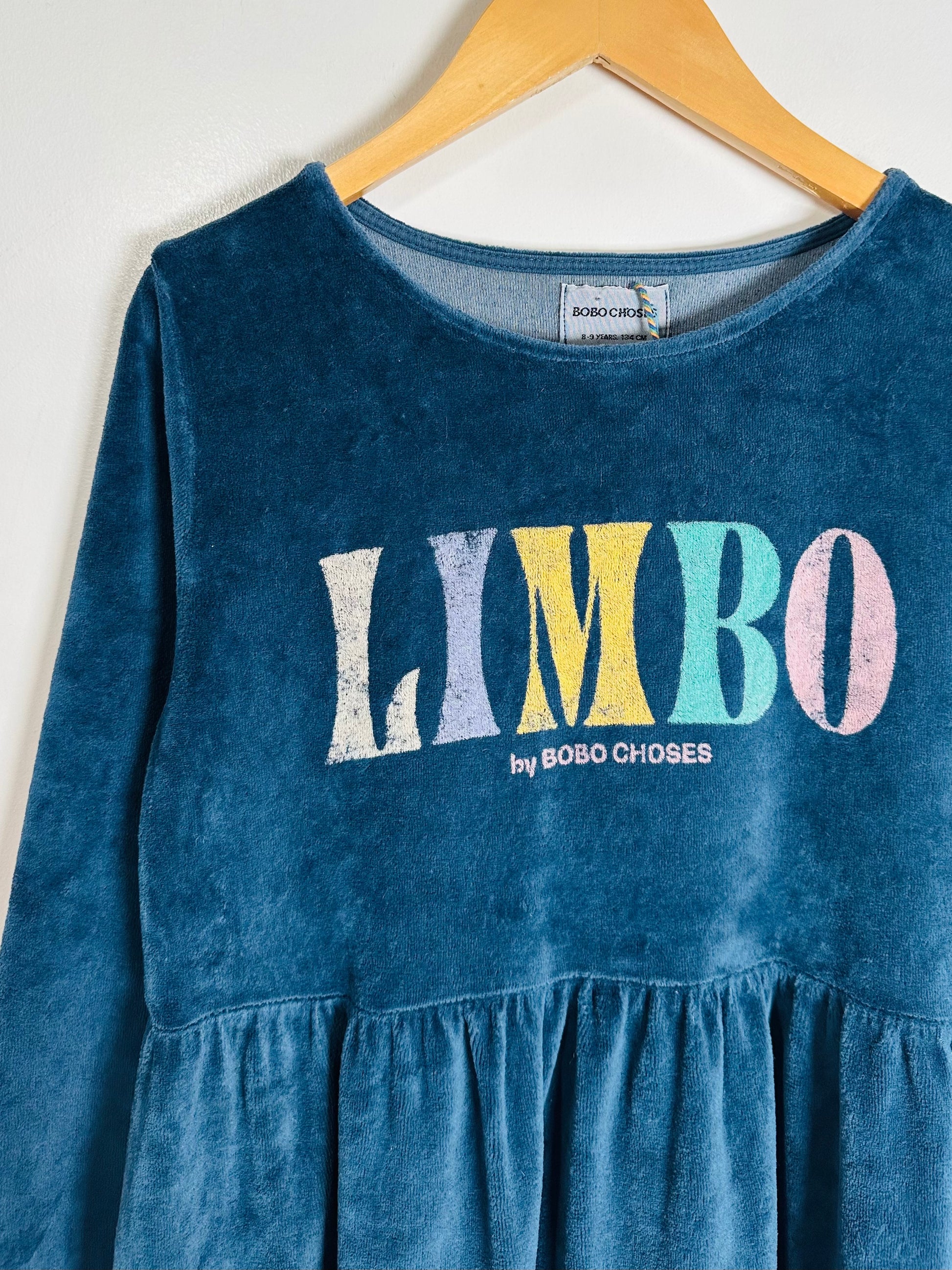 Blue dress with 'LIMBO by BOBO CHOSES' text on a hanger against a white background