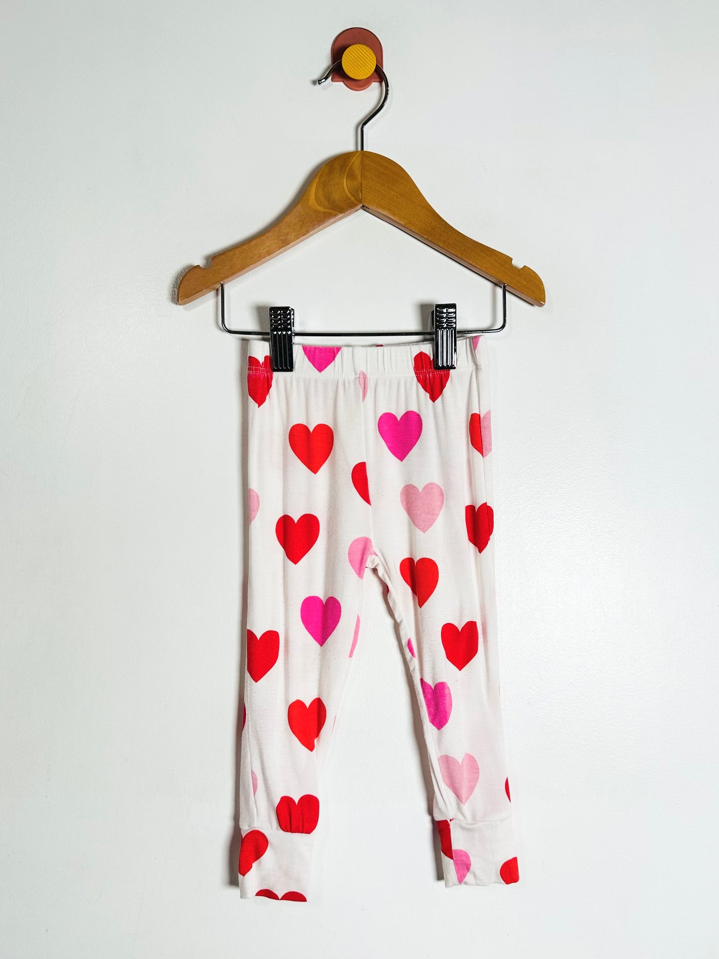 Heart-patterned pants on a hanger against a white background