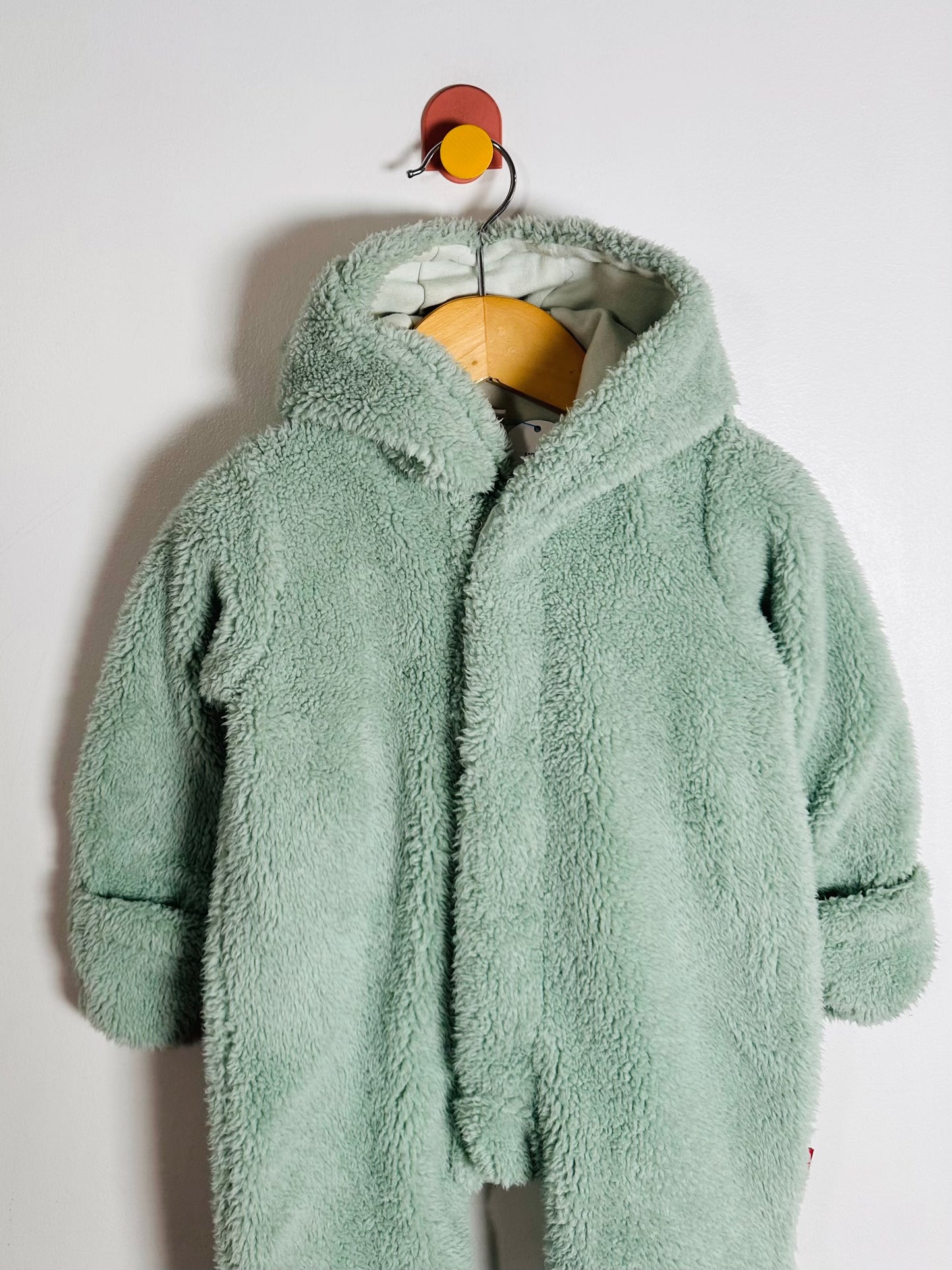 Green fluffy coat on a hanger against a white background