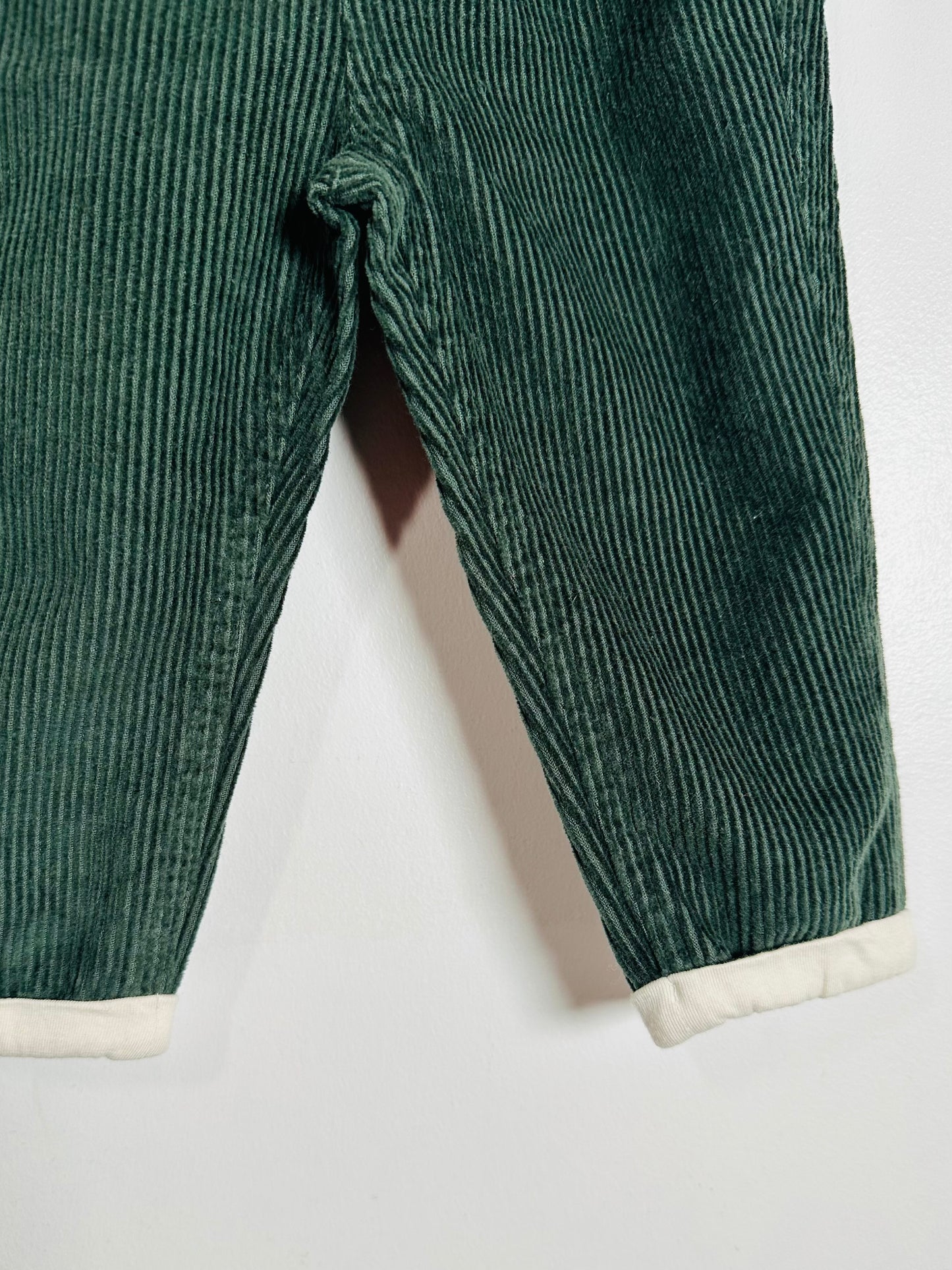 Green corduroy pants with white cuffs on a light gray background