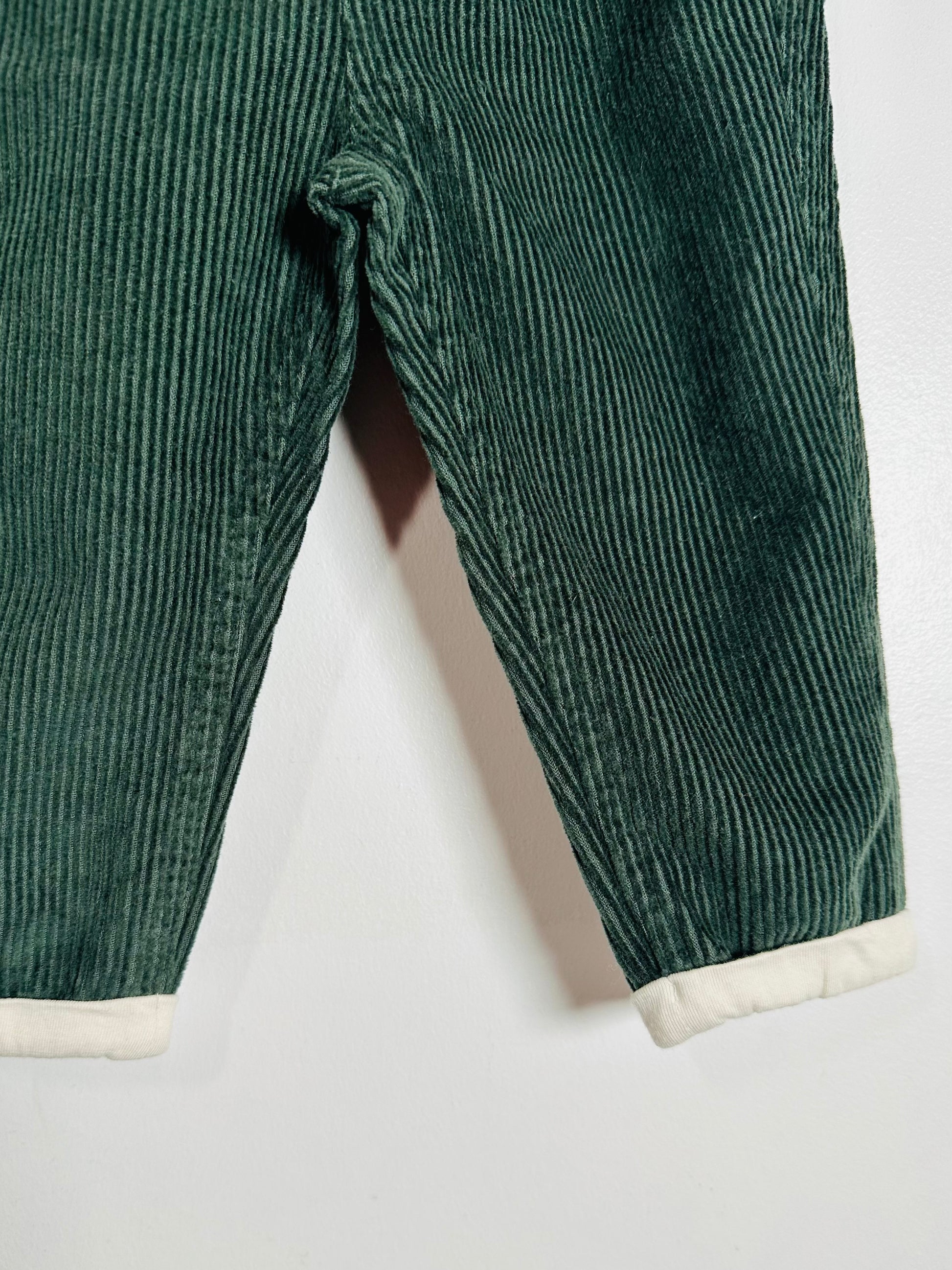 Green corduroy pants with white cuffs on a light gray background