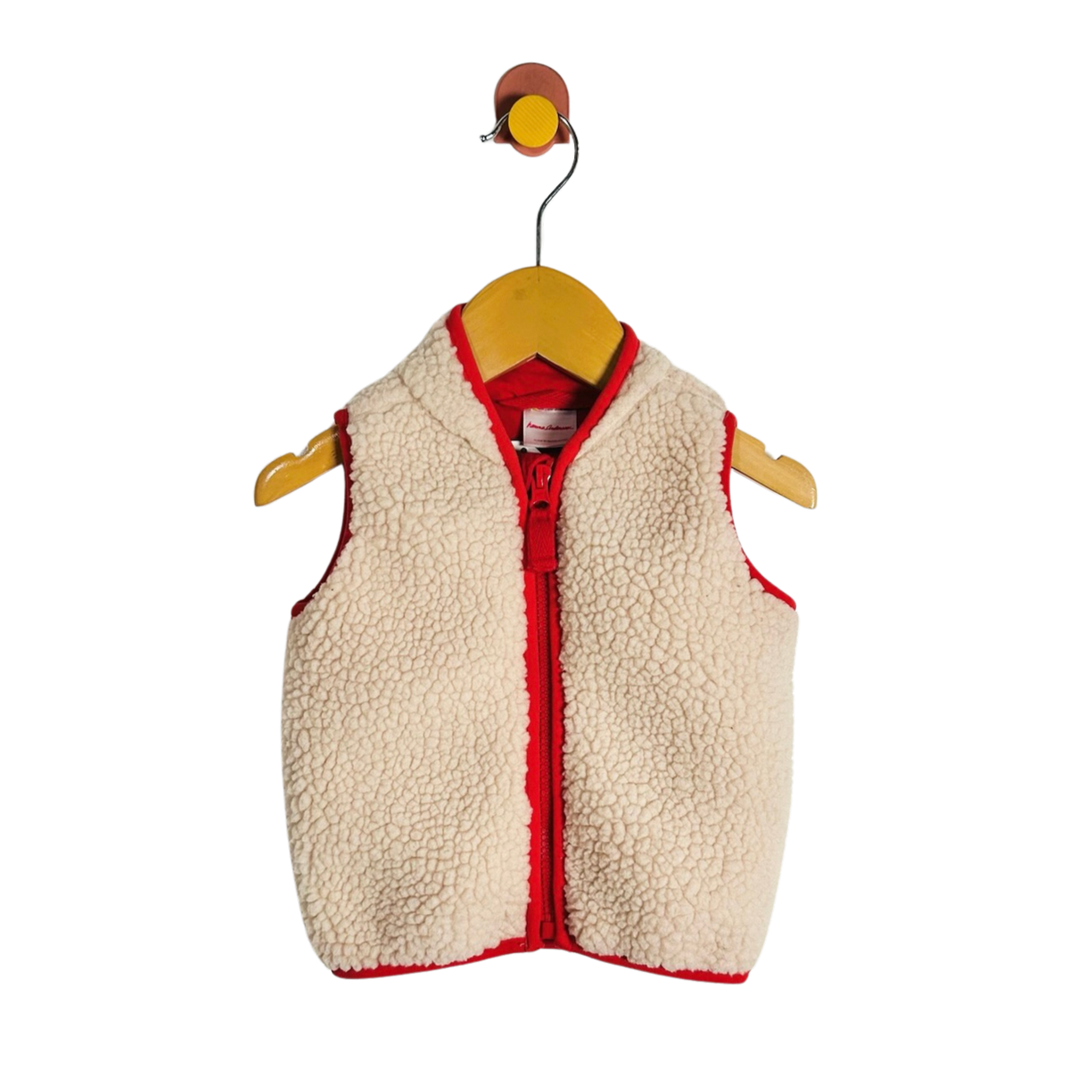 A cream sherpa fleece baby vest with red trim and a red zipper, hanging on a wooden hanger against a white background.