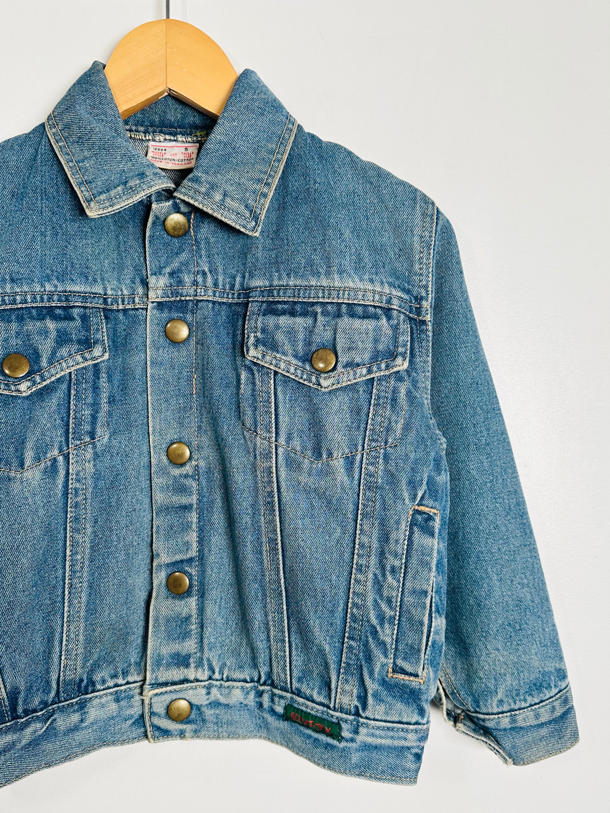 Blue denim jacket on a wooden hanger against a white background