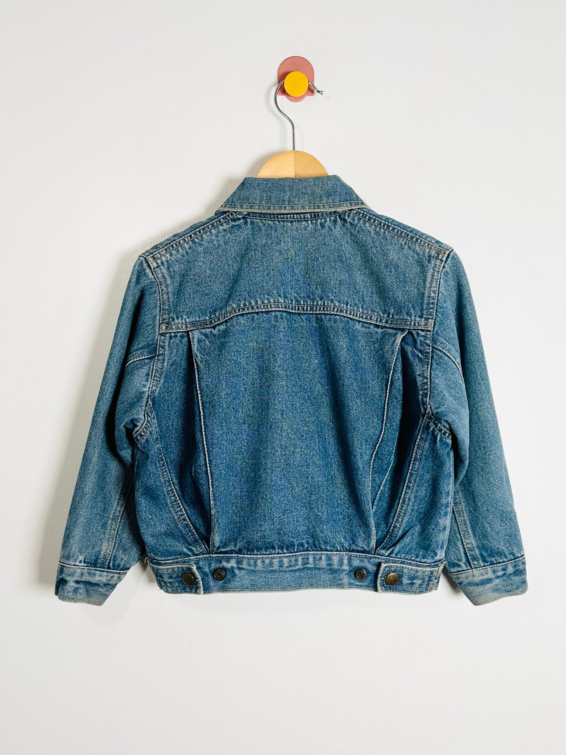 Blue denim jacket on a hanger against a white background