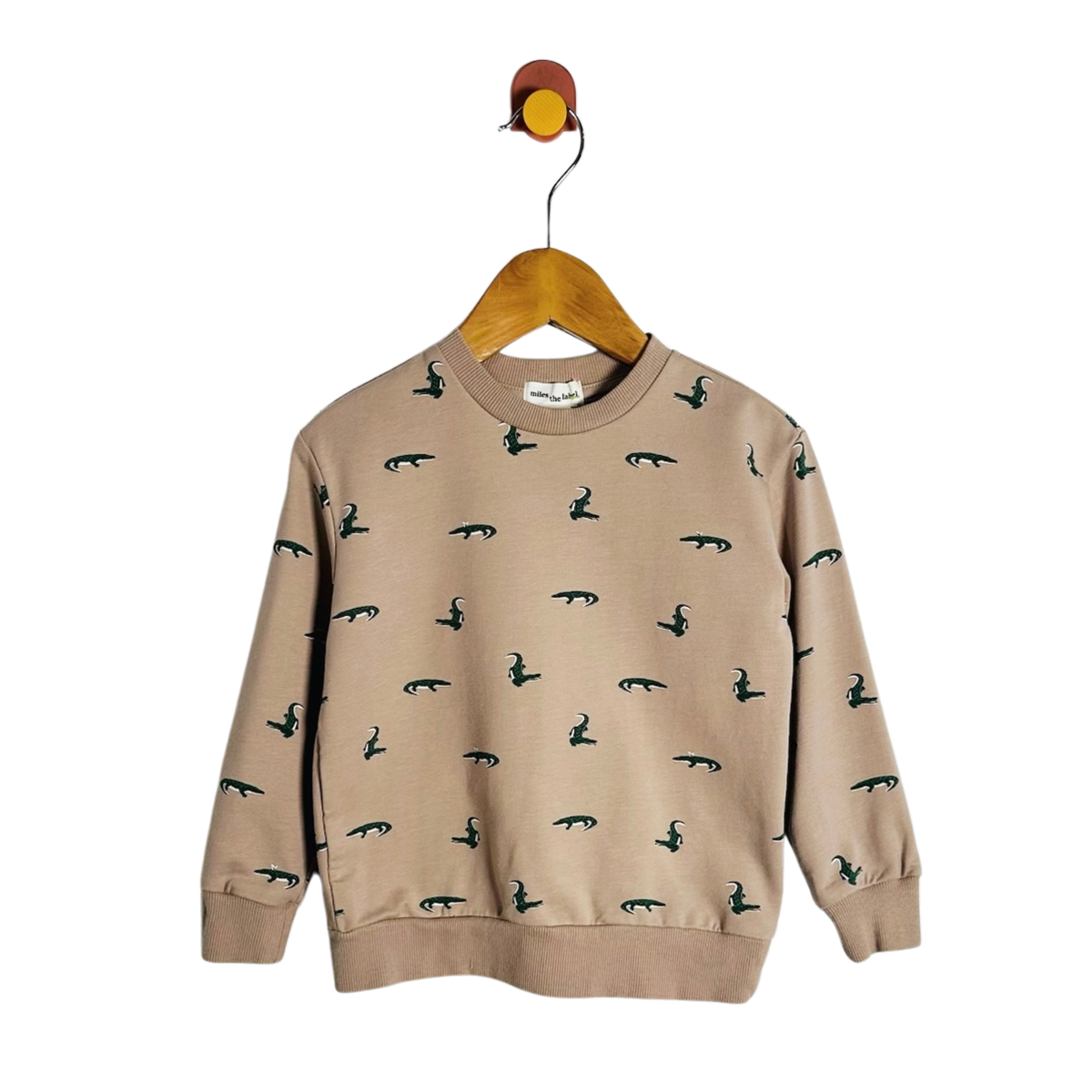 A beige crewneck sweatshirt with a repeating dark green bird pattern, hanging on a wooden hanger against a plain white background.