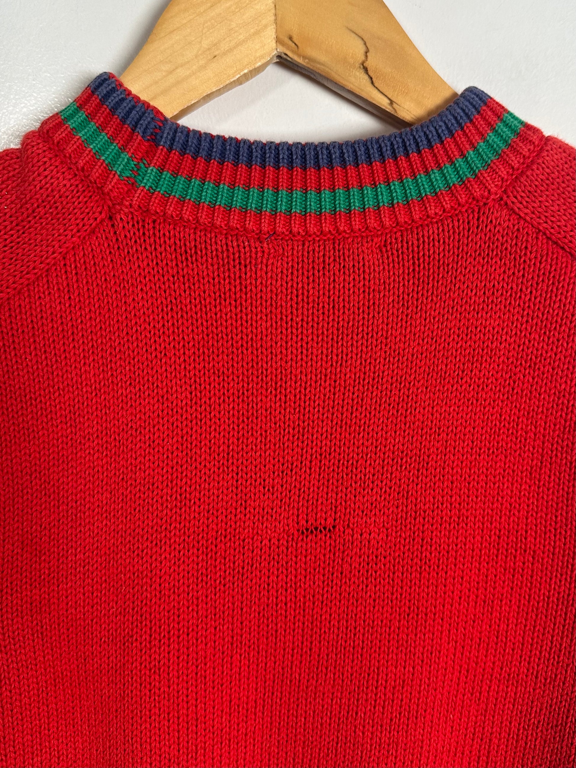 Red sweater with green and blue striped collar on a hanger