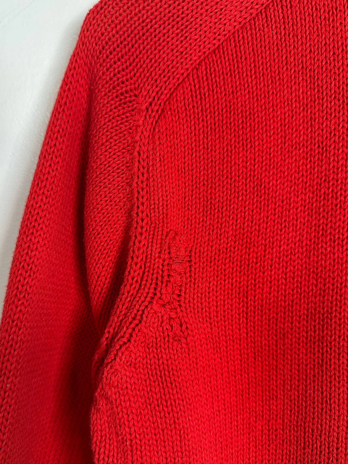 Close-up of a red knitted sweater on a light gray background