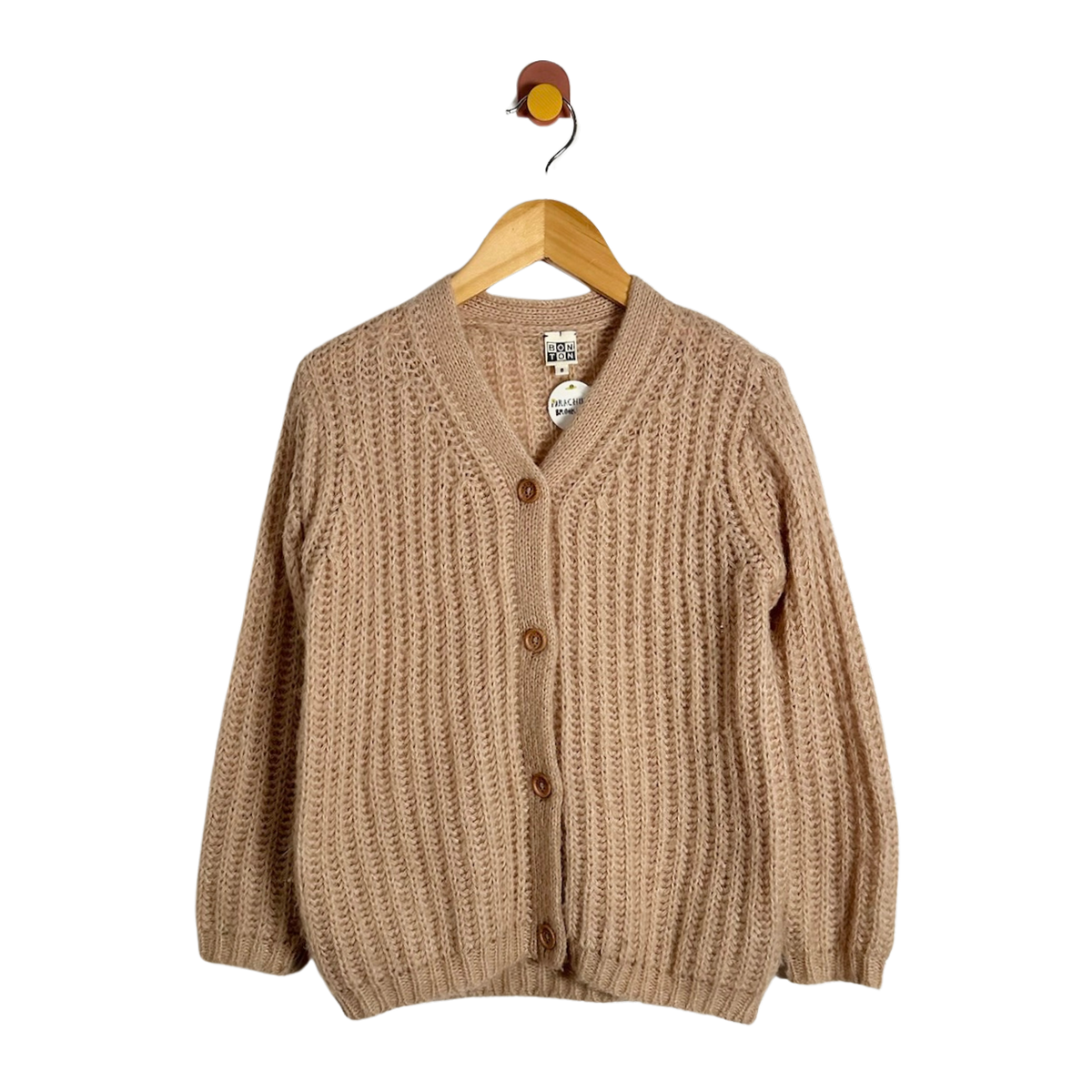 pink chunky knit cardigan sweater with a V-neck and brown buttons, hanging on a wooden hanger against a plain white background.