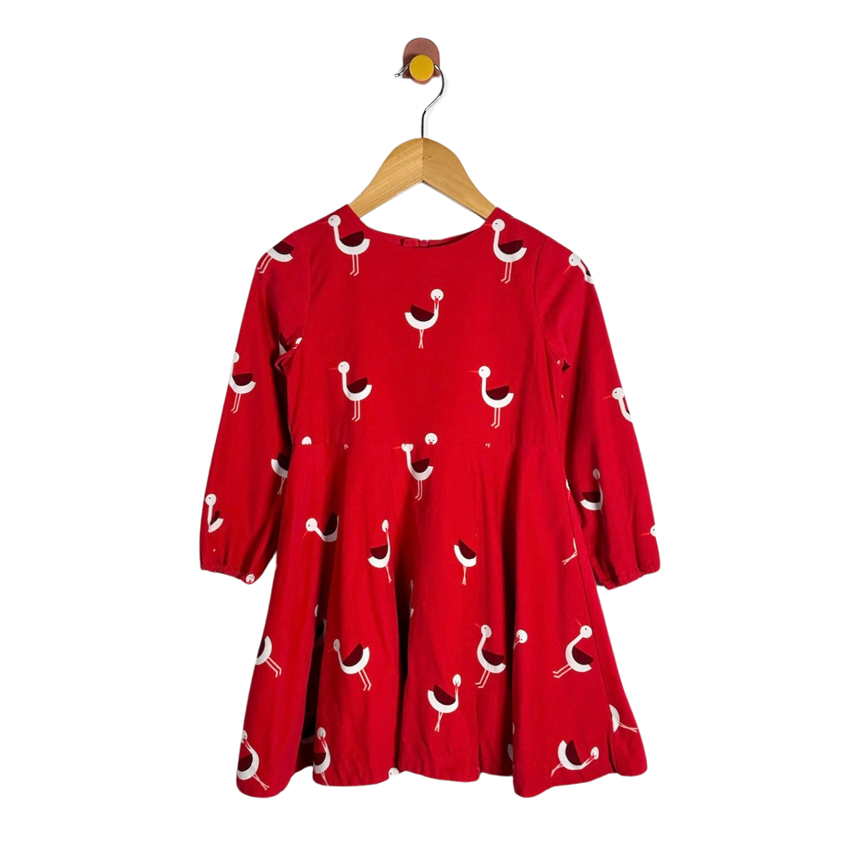A red long-sleeve dress with a white and black bird pattern, hanging on a wooden hanger against a plain white background.
