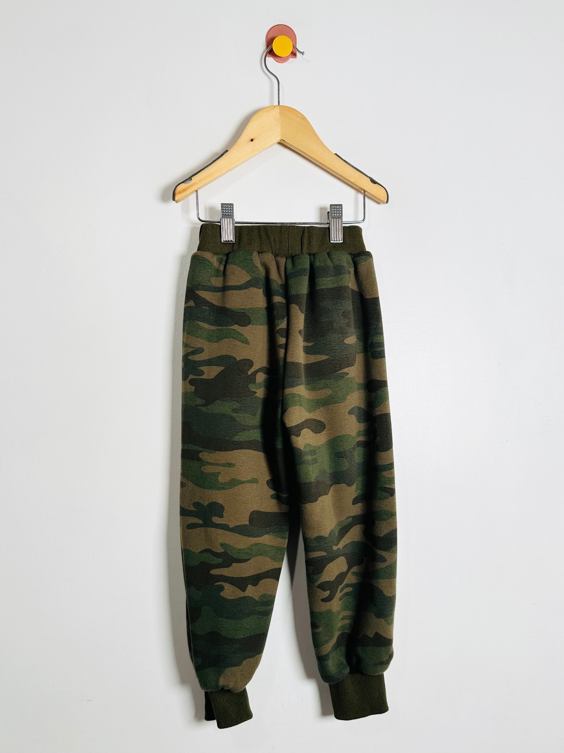 Camouflage pants on a hanger against a white background