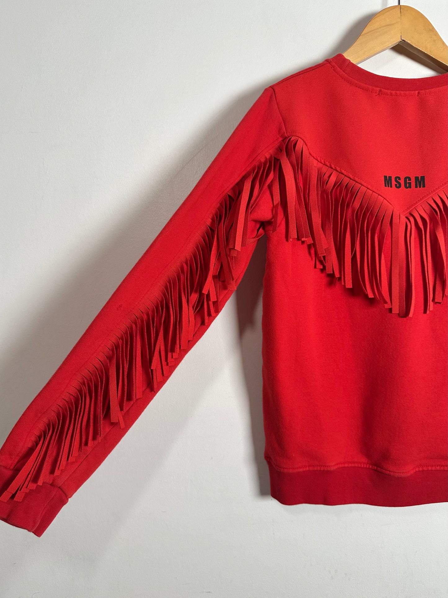 Red sweatshirt with fringe details and 'MSGM' branding on a white background