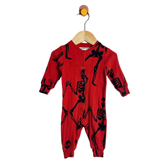 Red baby onesie with black skeleton patterns on a hanger against a white background