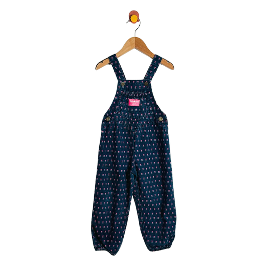 A pair of toddler's dark blue denim overall jumpsuit with a small white and yellow pattern, hanging on a wooden hanger against a white background.