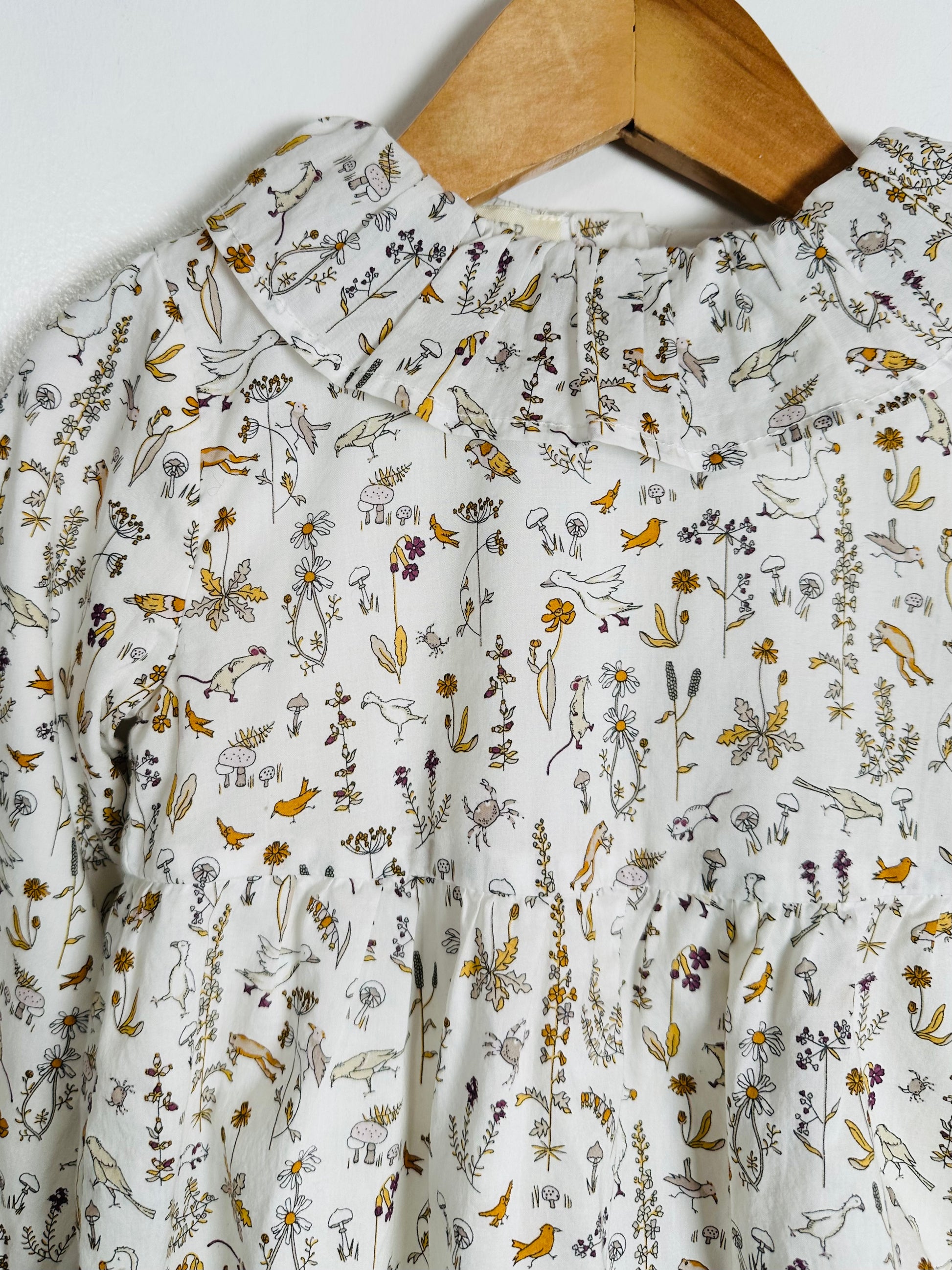 Floral patterned shirt on a wooden hanger against a white background