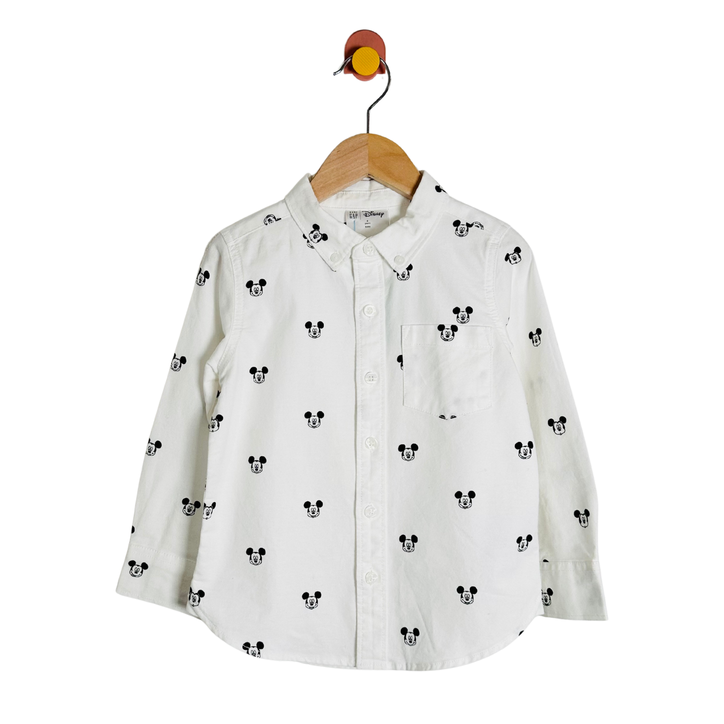 White shirt with black mickey mouse head pattern on a hanger against a white background