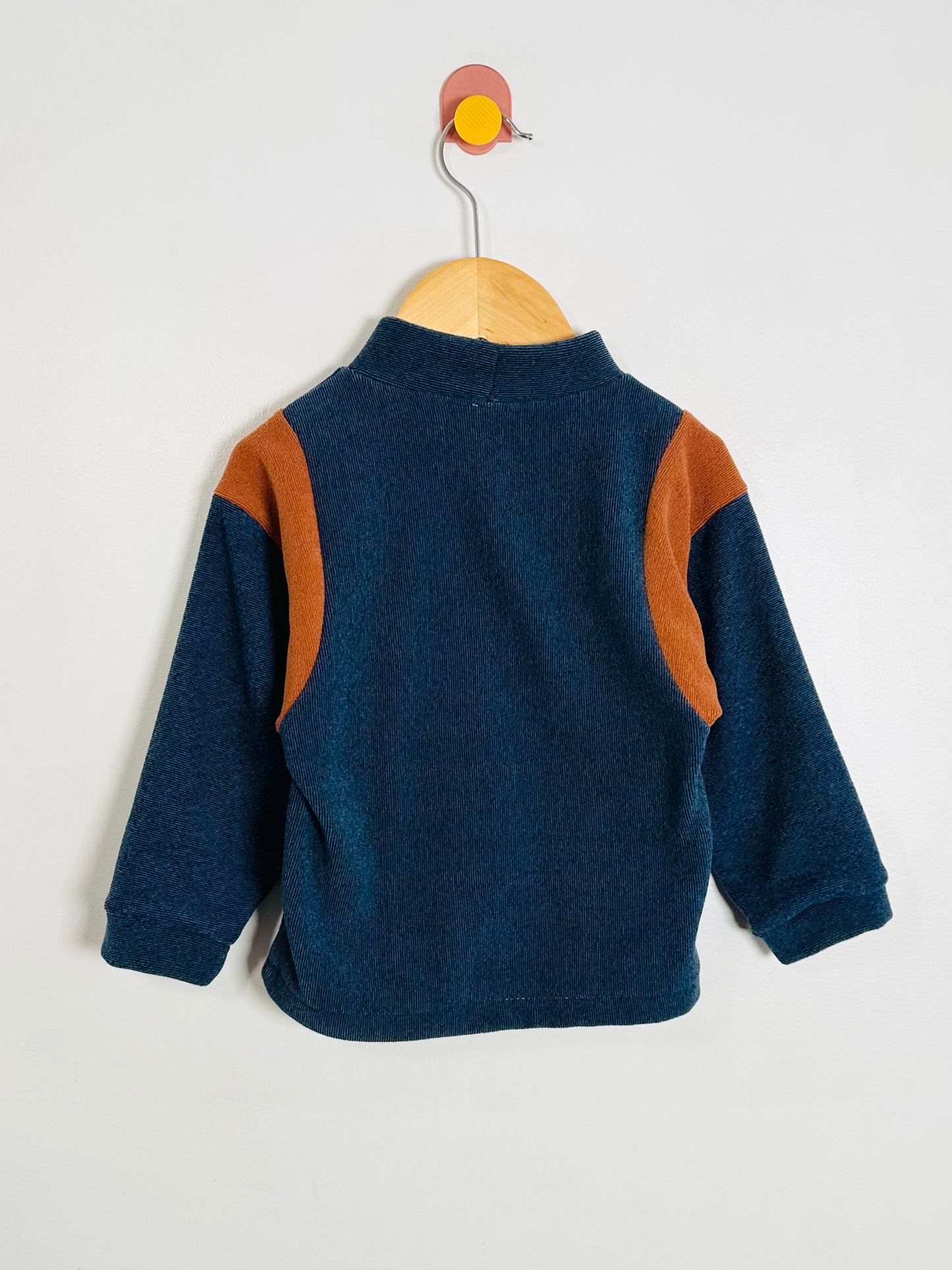 Children's blue fleece sweater with brown sleeves on a hanger against a white background