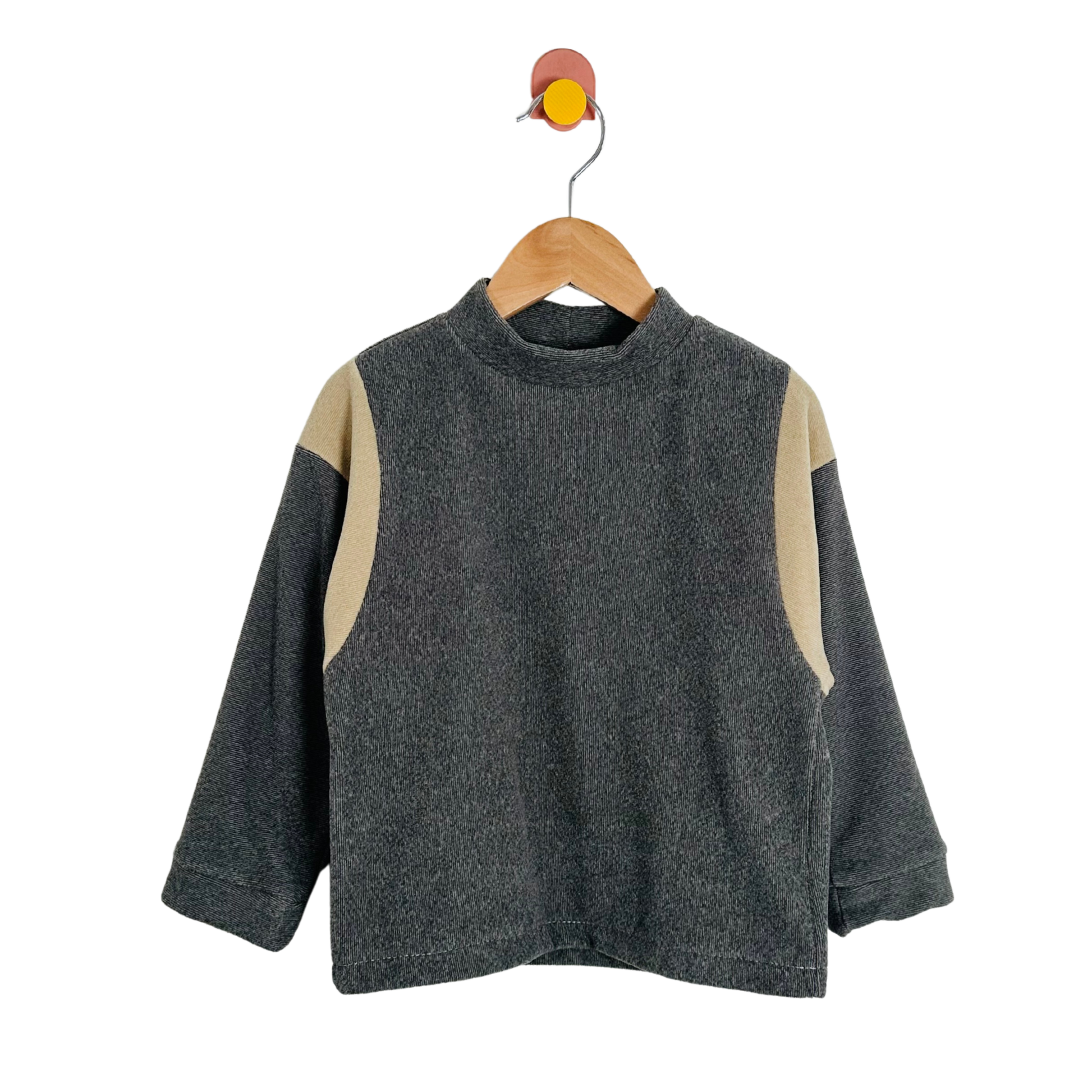 Gray sweater with beige sleeves on a wooden hanger against a white background