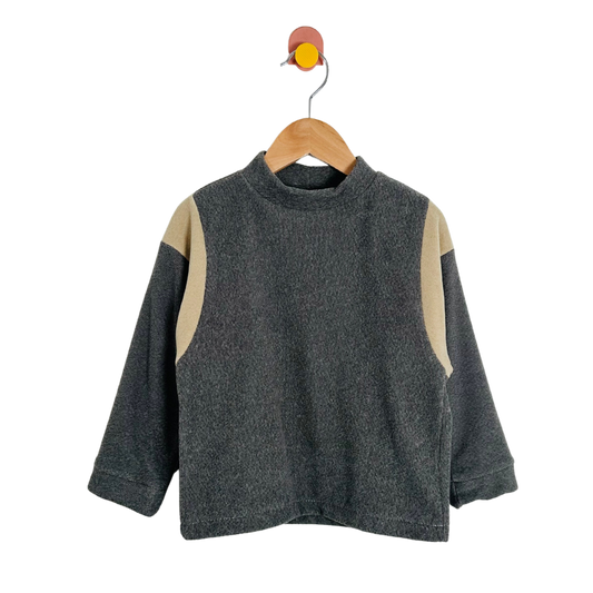 Gray sweater with beige sleeves on a wooden hanger against a white background