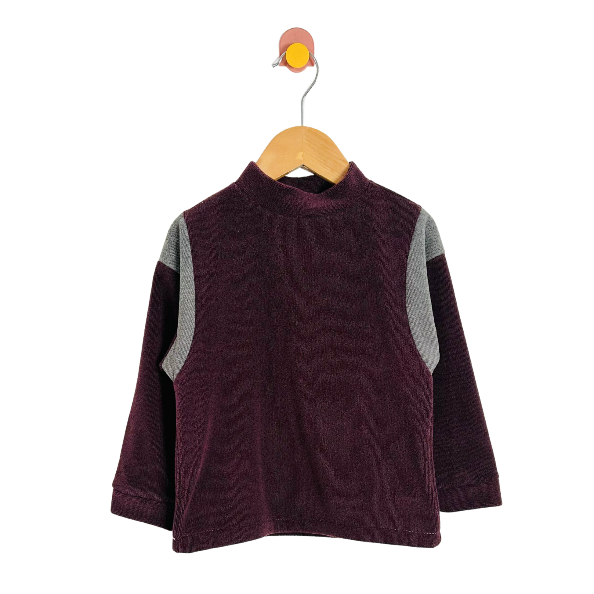 Children's purple sweater with gray sleeves on a wooden hanger against a white background