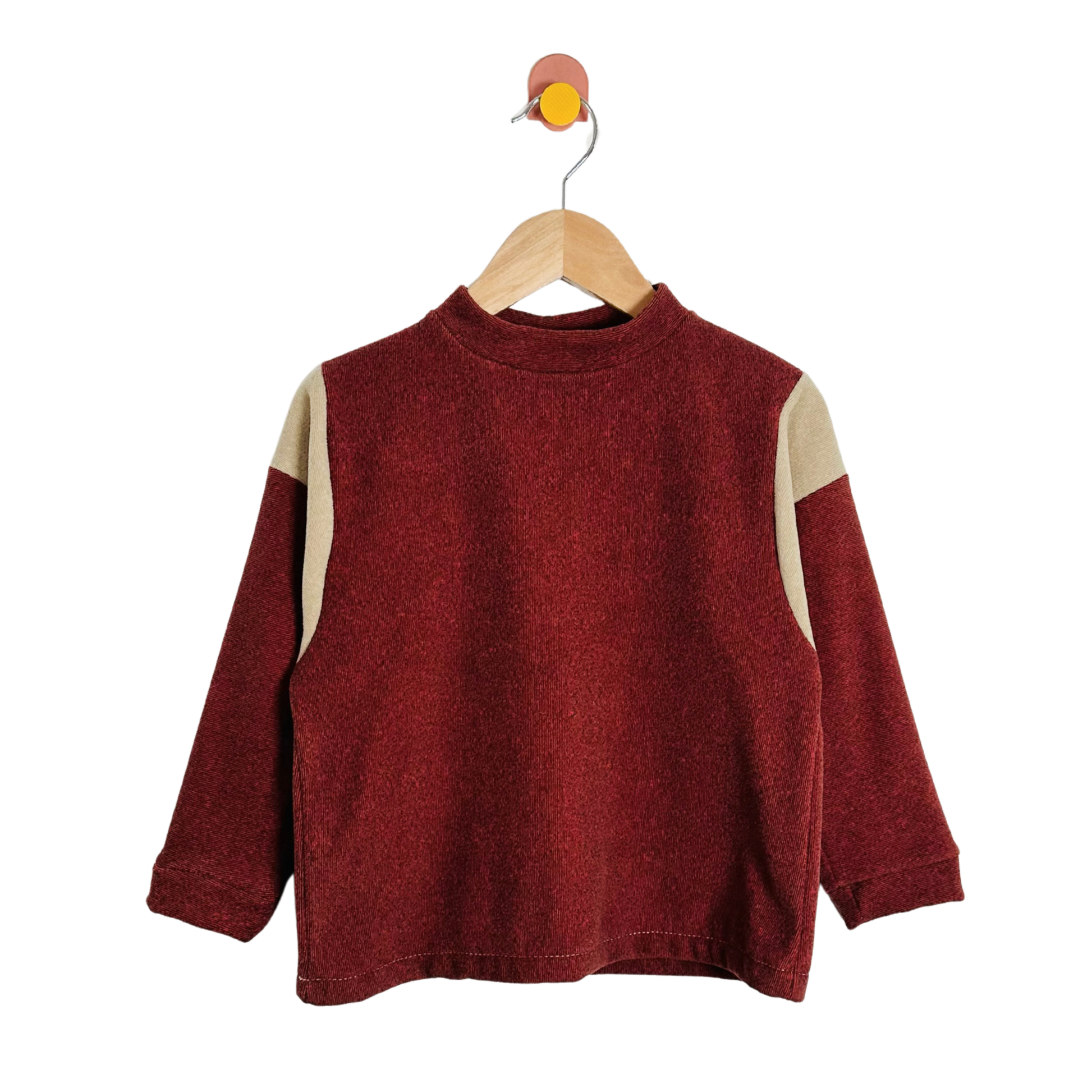 Red sweater with beige sleeves on a wooden hanger against a white background