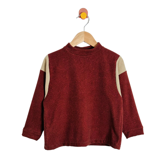 Red sweater with beige sleeves on a wooden hanger against a white background