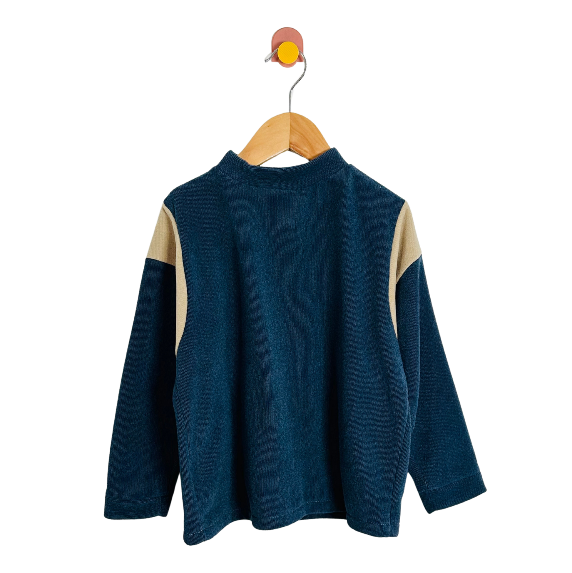 Blue sweater with beige sleeves on a wooden hanger against a white background