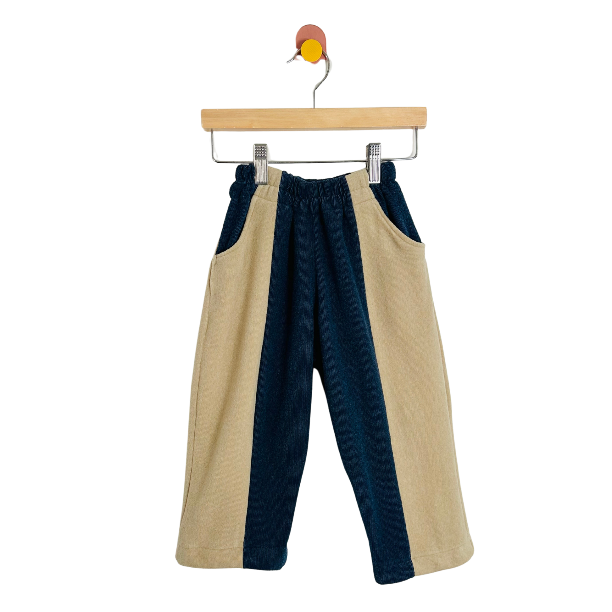 Two-tone pants with beige and navy blue on a hanger against a white background