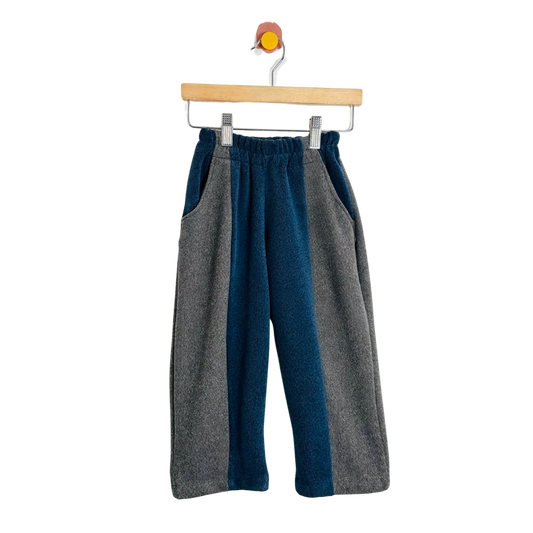 Two-tone gray and blue pants on a hanger against a white background