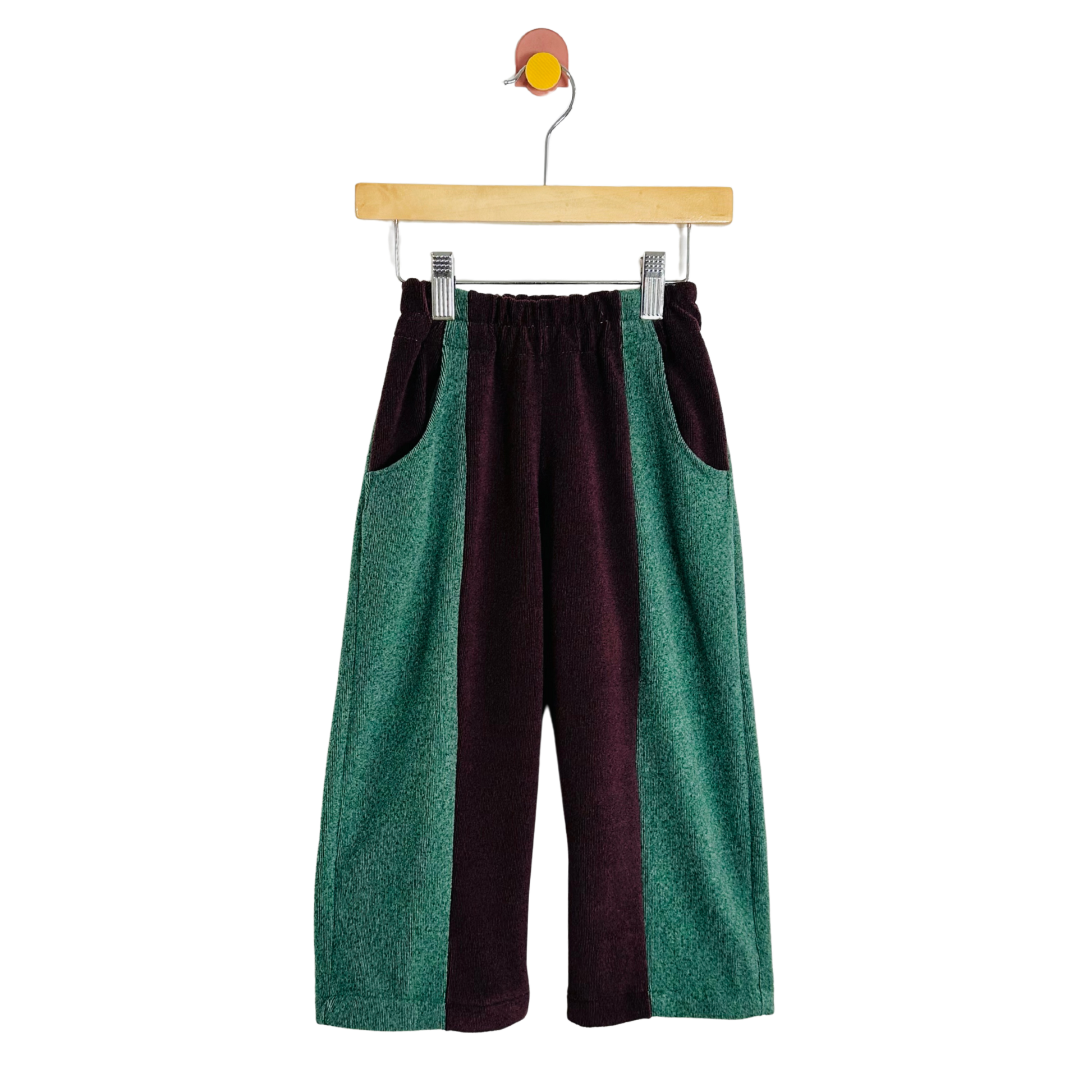 Two-tone green and maroon pants on a hanger against a white background