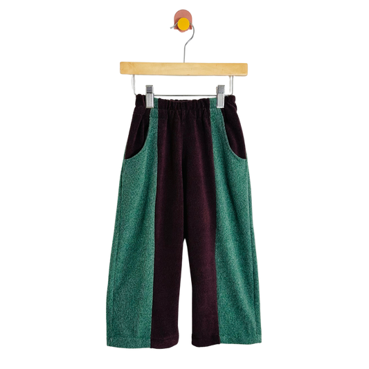 Two-tone green and maroon pants on a hanger against a white background