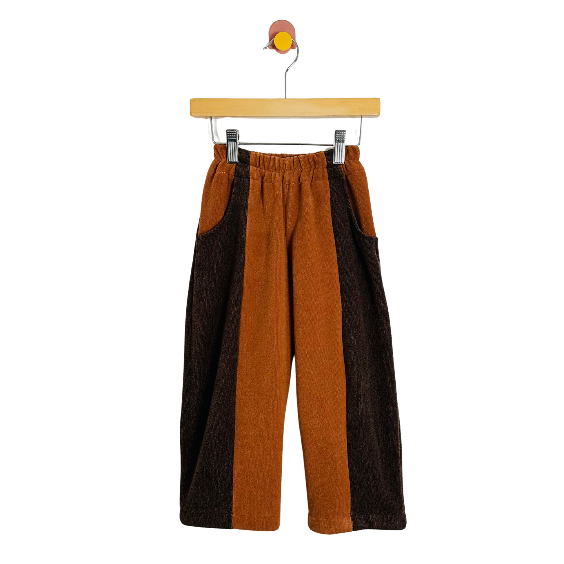 Brown and orange pants on a hanger against a white background