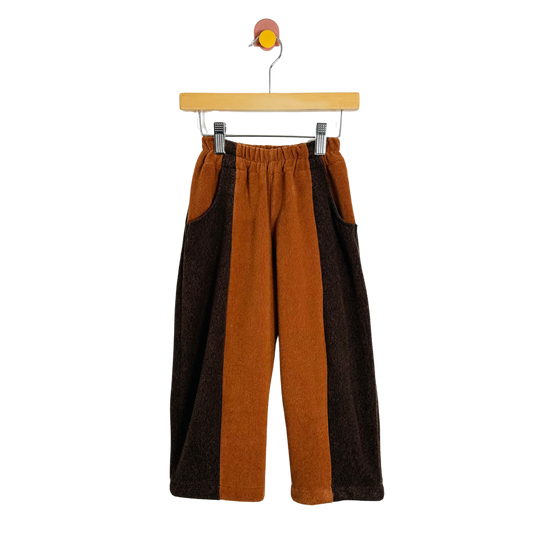 Brown and orange pants on a hanger against a white background