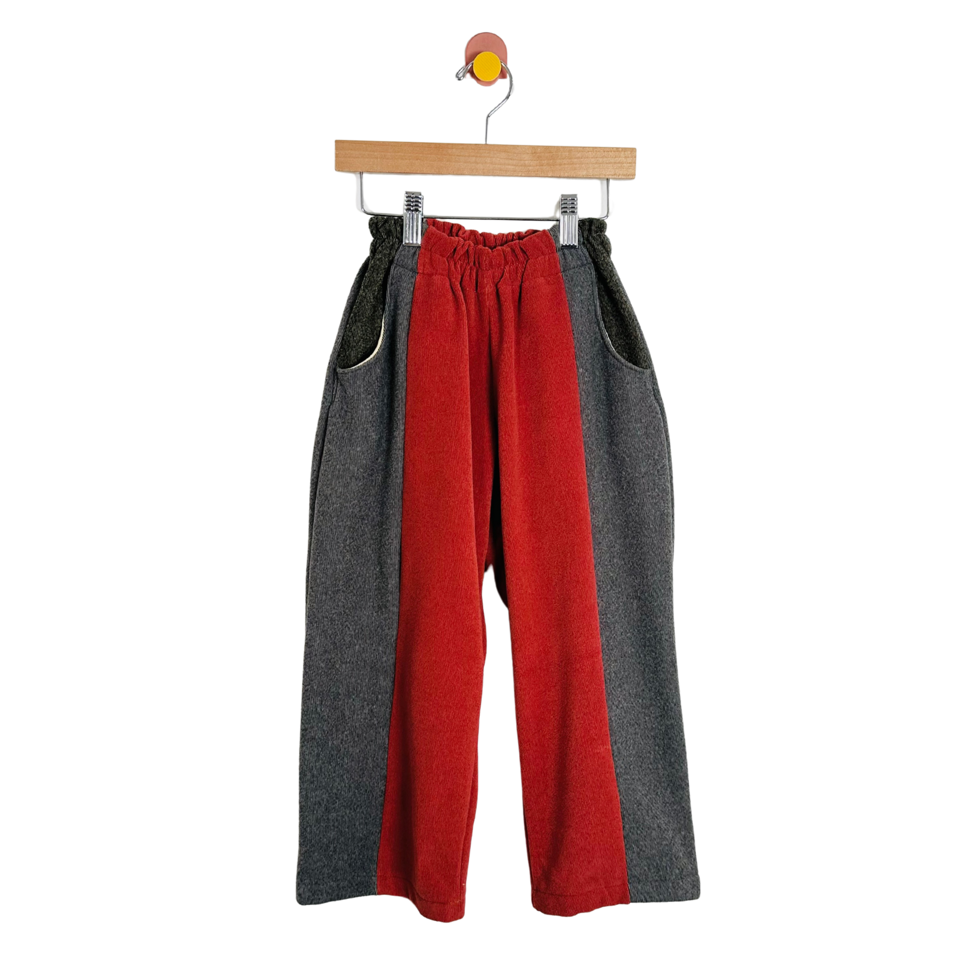 Red and gray pants on a hanger against a white background