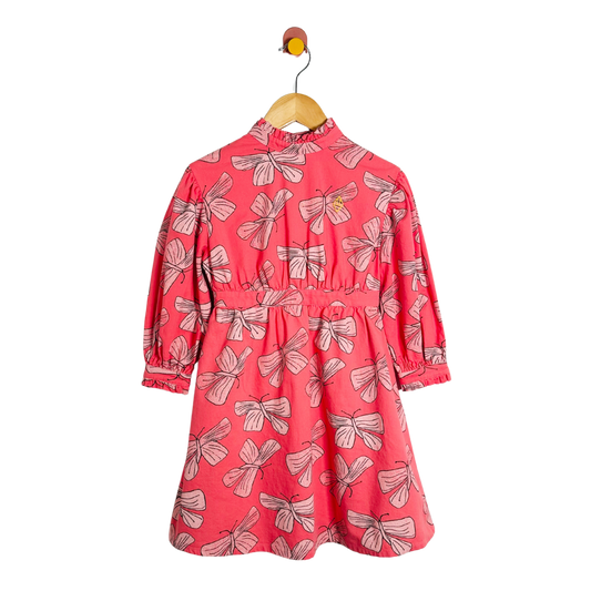 Red dress with butterfly pattern on a hanger against a white background
