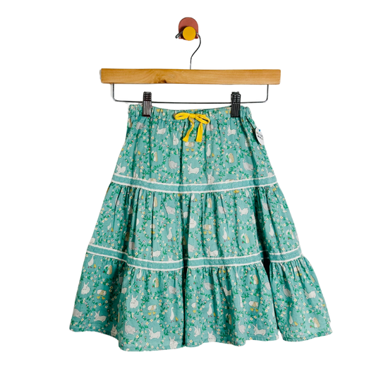 Green floral skirt with a yellow ribbon on a wooden hanger against a white background