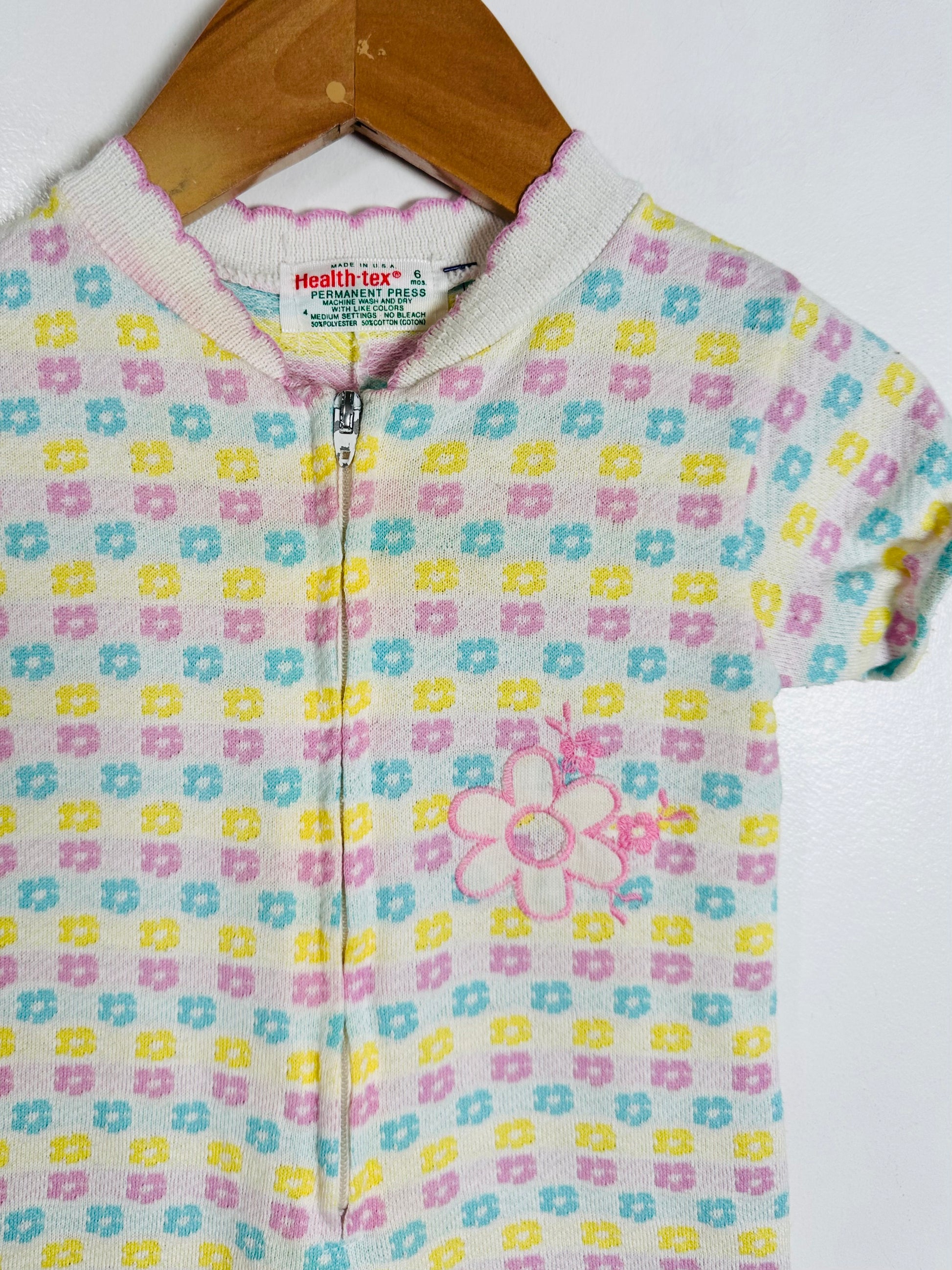 Children's onesie with floral pattern on a hanger