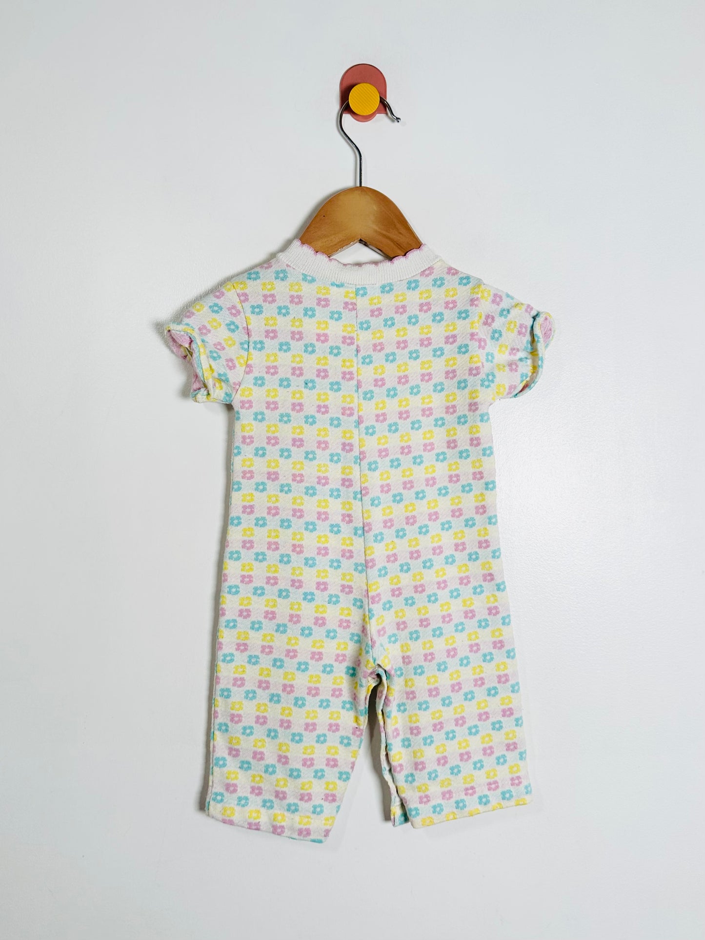 Children's floral patterned onesie on a hanger against a white background