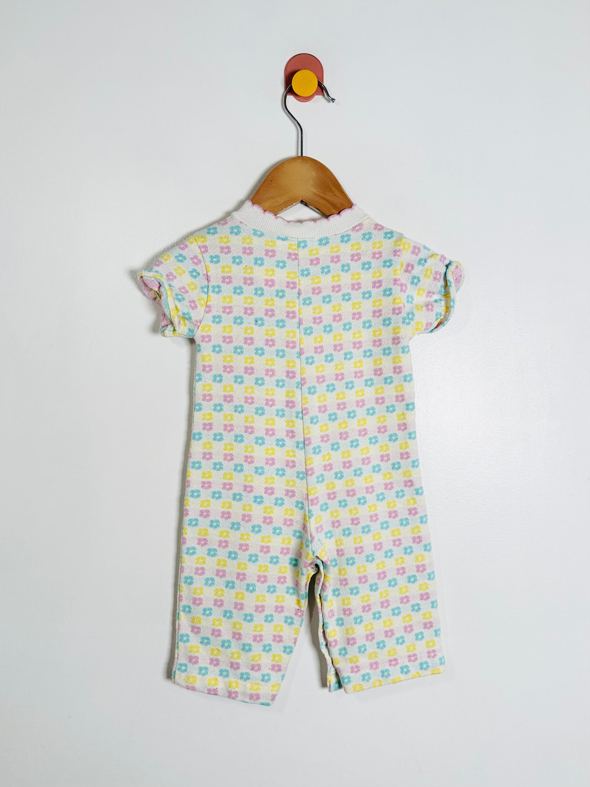 Children's floral patterned onesie on a hanger against a white background