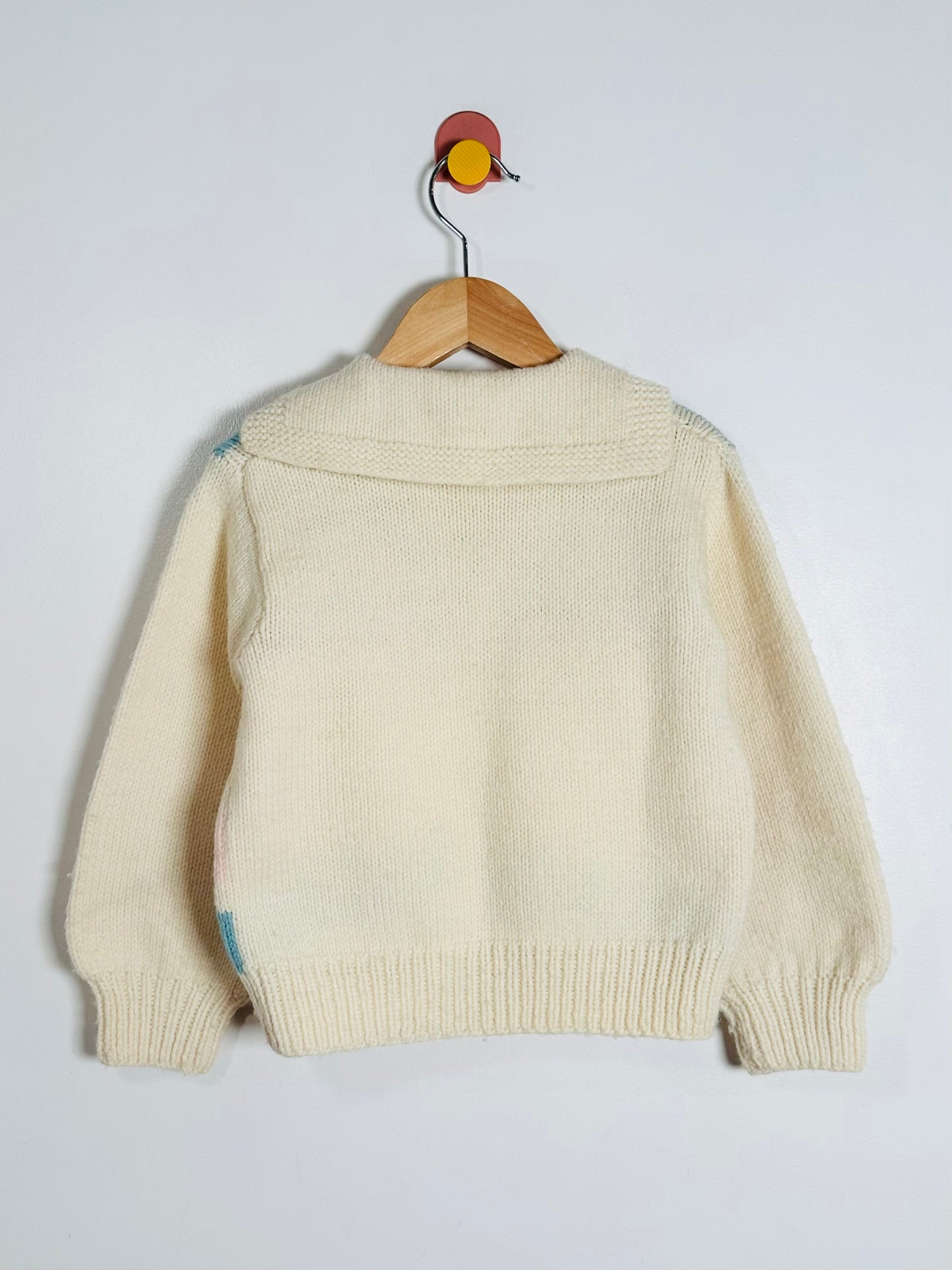Beige sweater on a wooden hanger against a white background