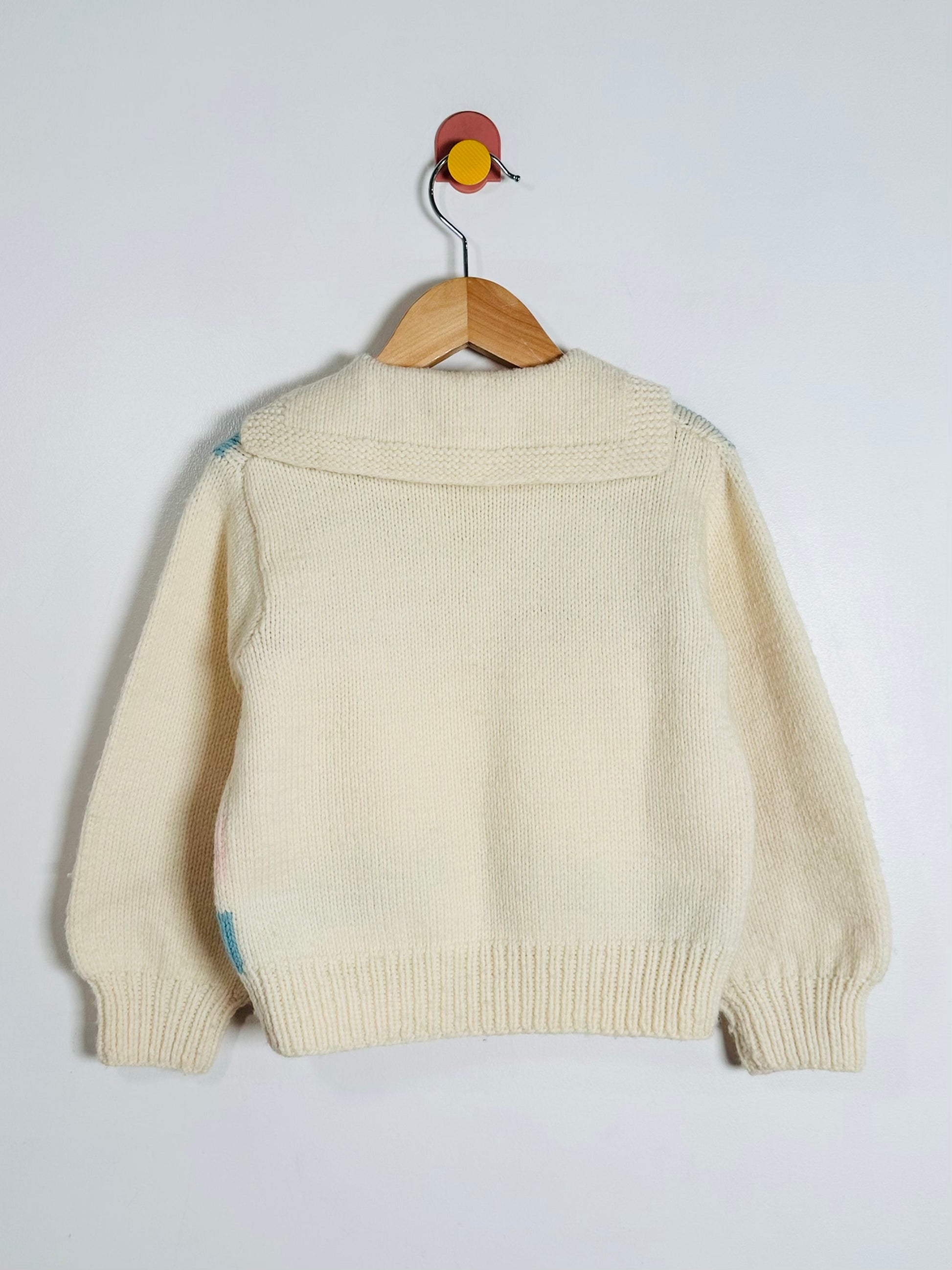 Beige sweater on a wooden hanger against a white background