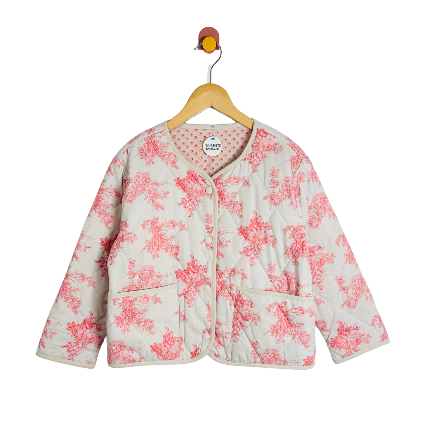 Floral-patterned jacket on a hanger against a white background