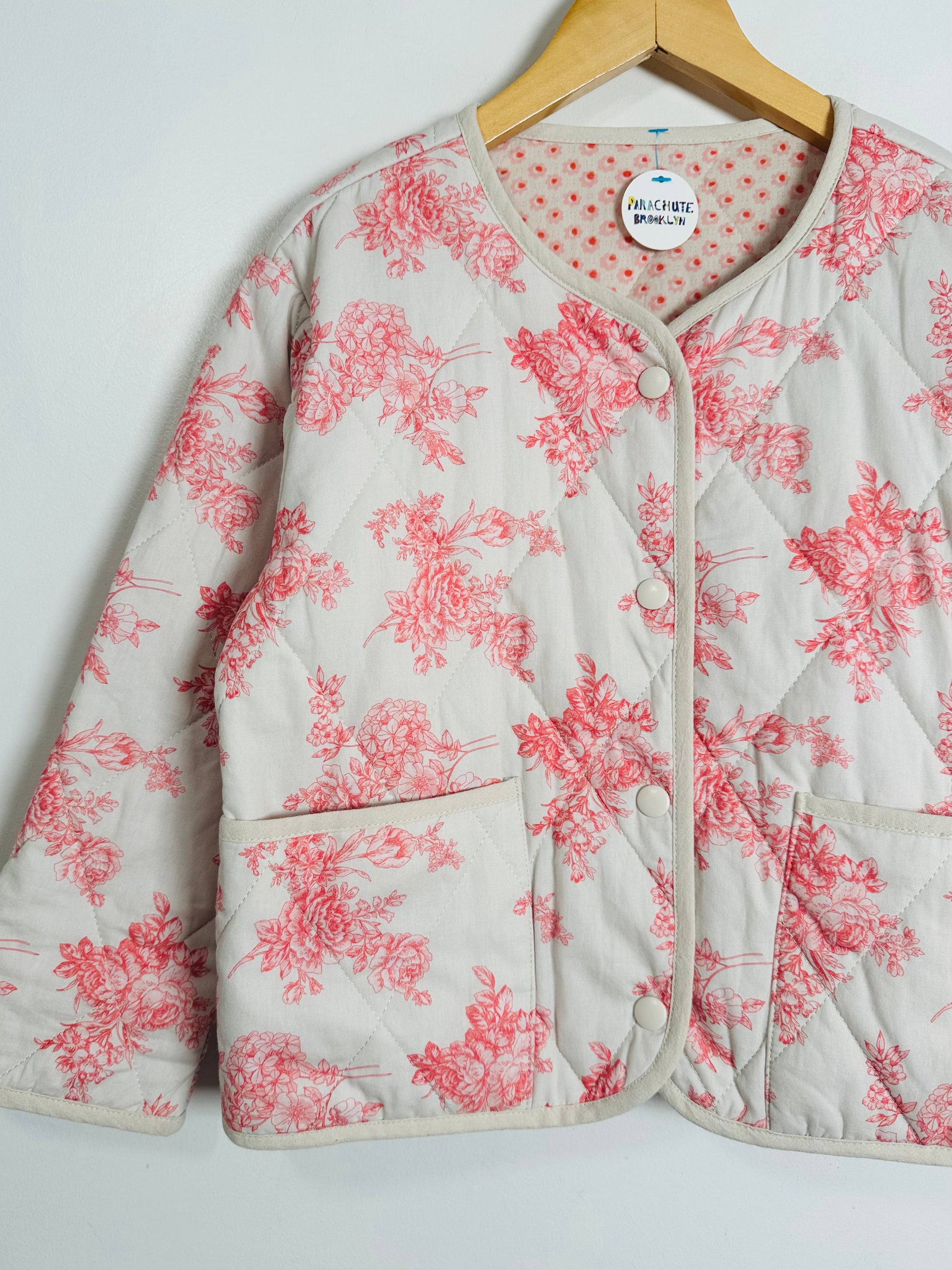 Floral-patterned jacket on a hanger against a white background