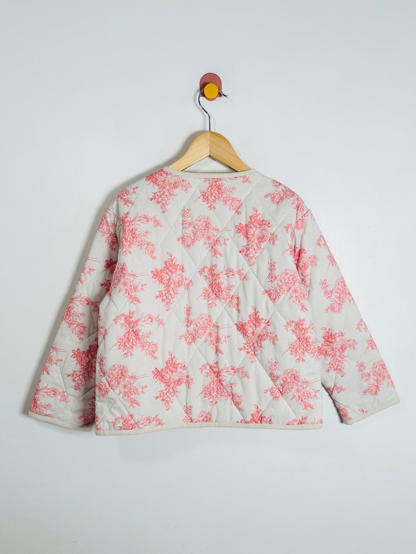 Floral-patterned jacket on a hanger against a white background