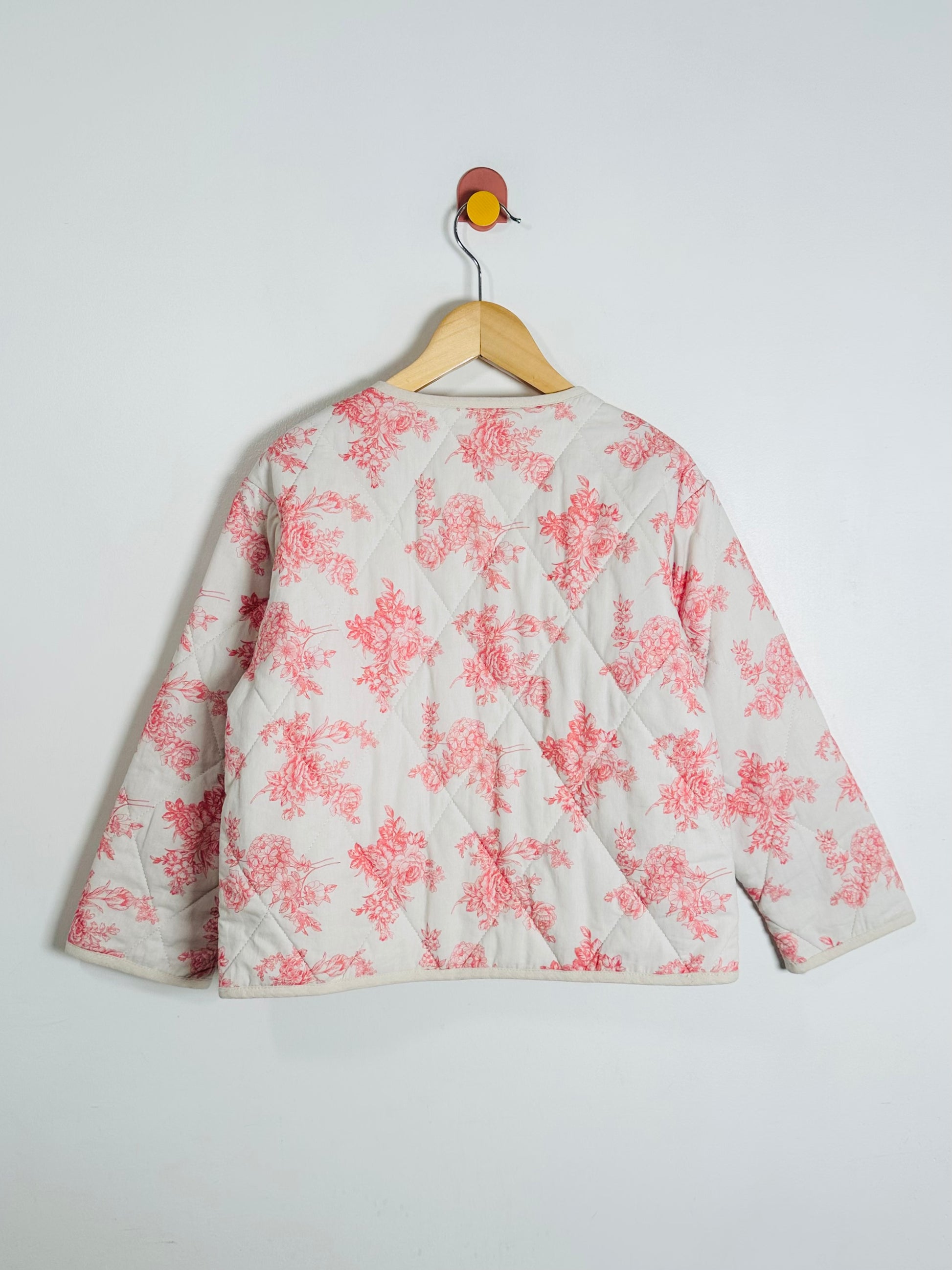 Floral-patterned jacket on a hanger against a white background