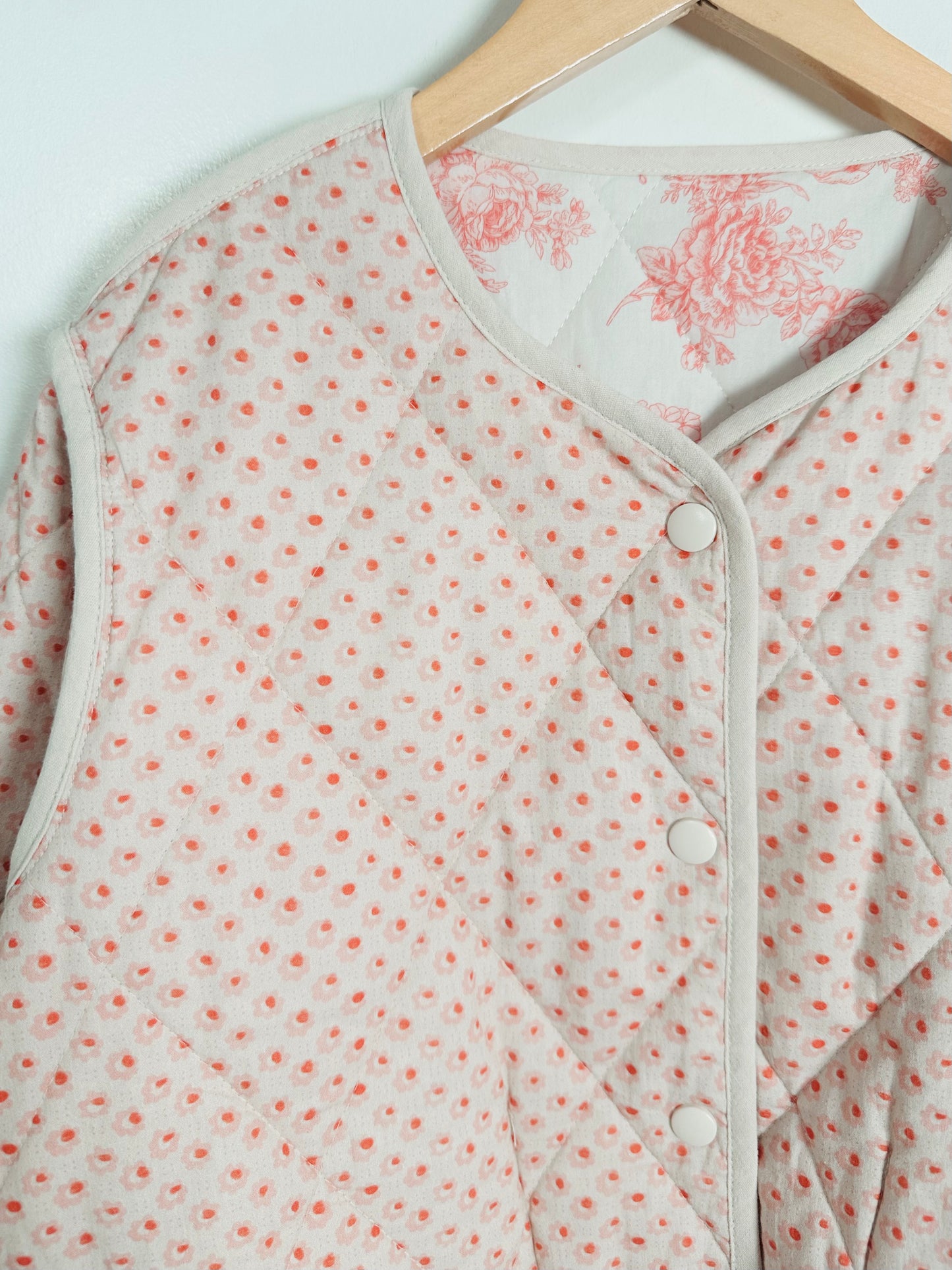 Baby outfit with floral pattern on a hanger against a light background