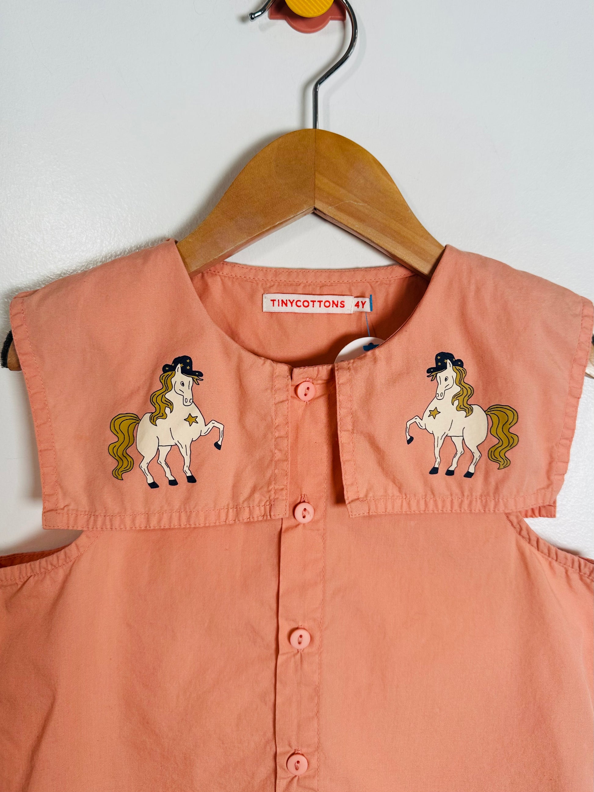 Pink children's shirt with horse designs on a hanger